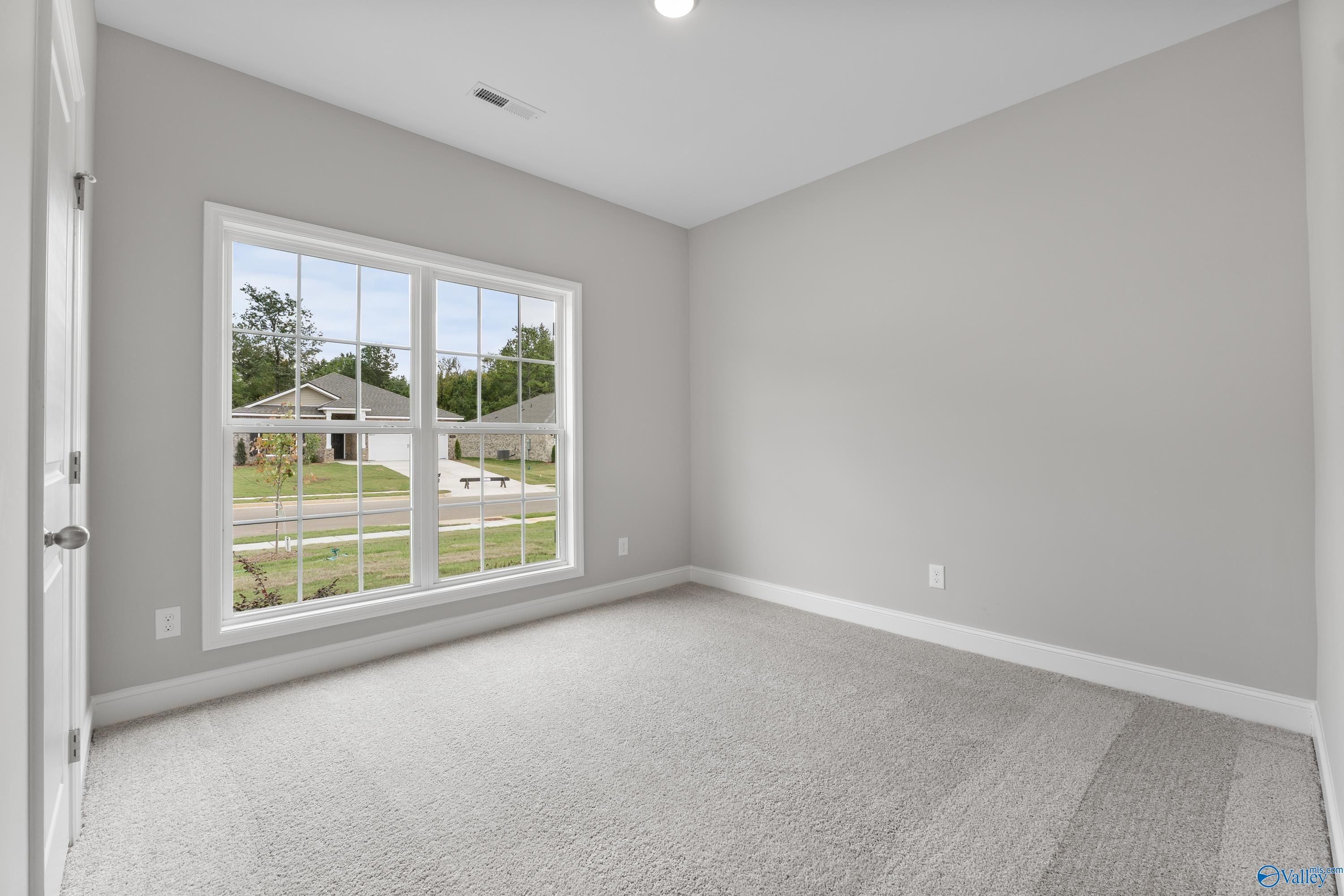 Bright secondary bedroom with large window view of suburban yard in Davidson Homes The Franklin C, Huntsville, Alabama