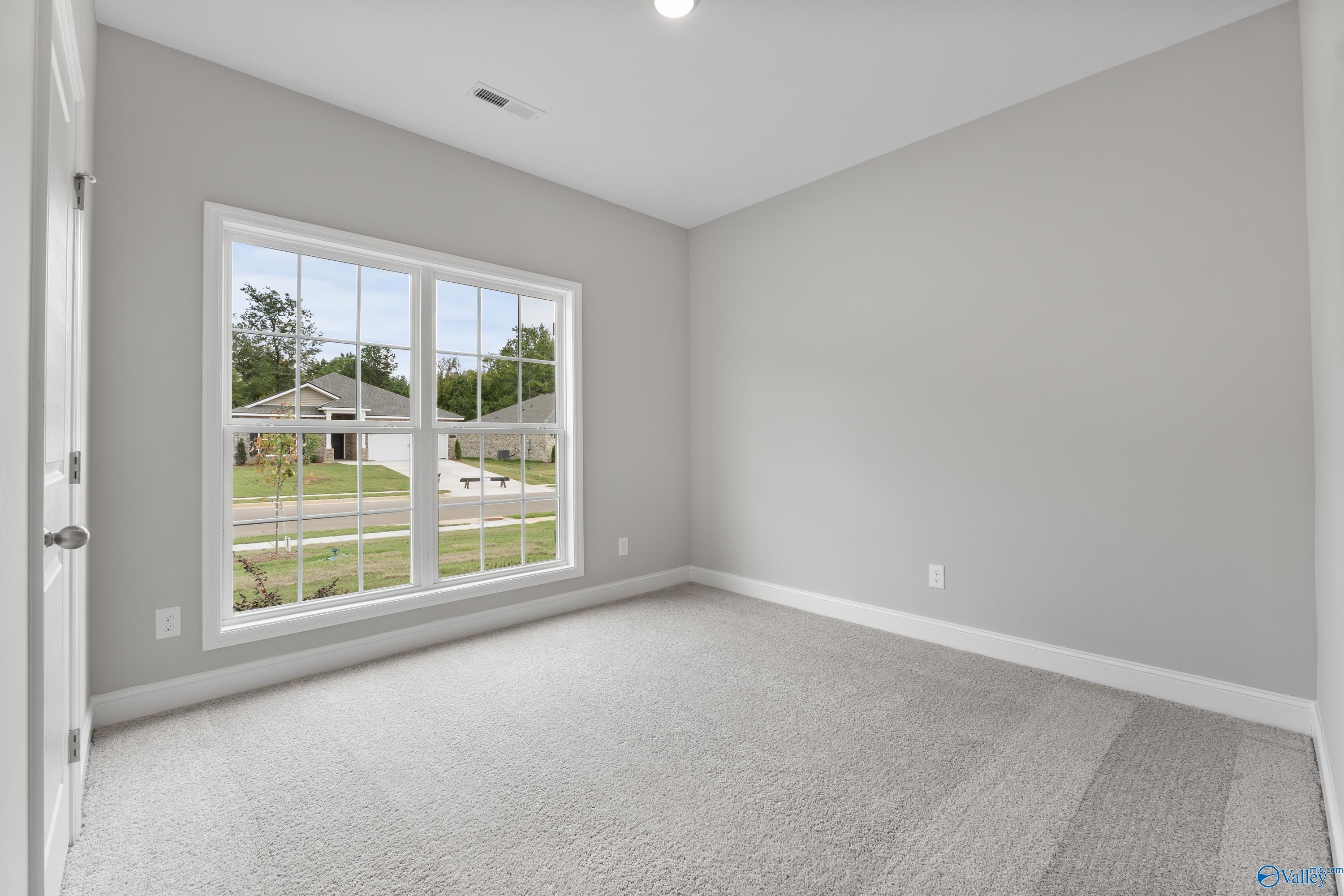 Bright secondary bedroom with large window view of suburban yard in Davidson Homes The Franklin C, Huntsville, Alabama