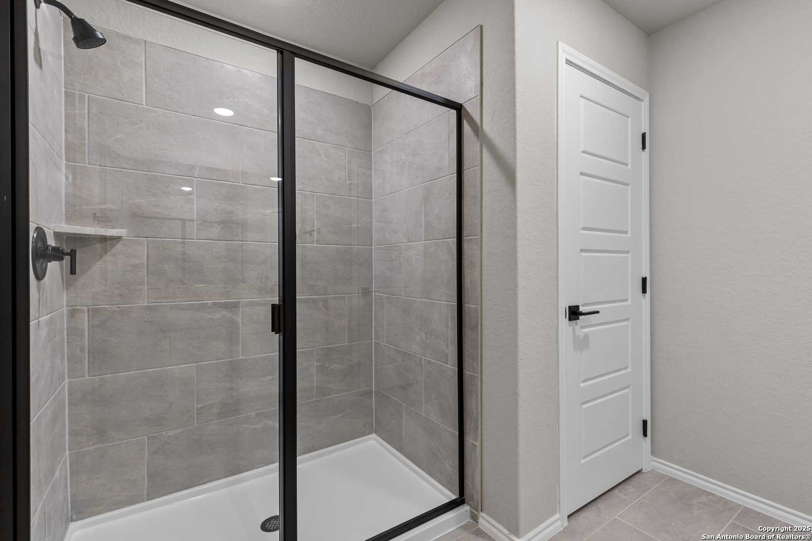 Modern frameless glass shower with gray subway tiles and built-in shelf in master bath of Davidson Homes The Murray I, San Antonio, TX