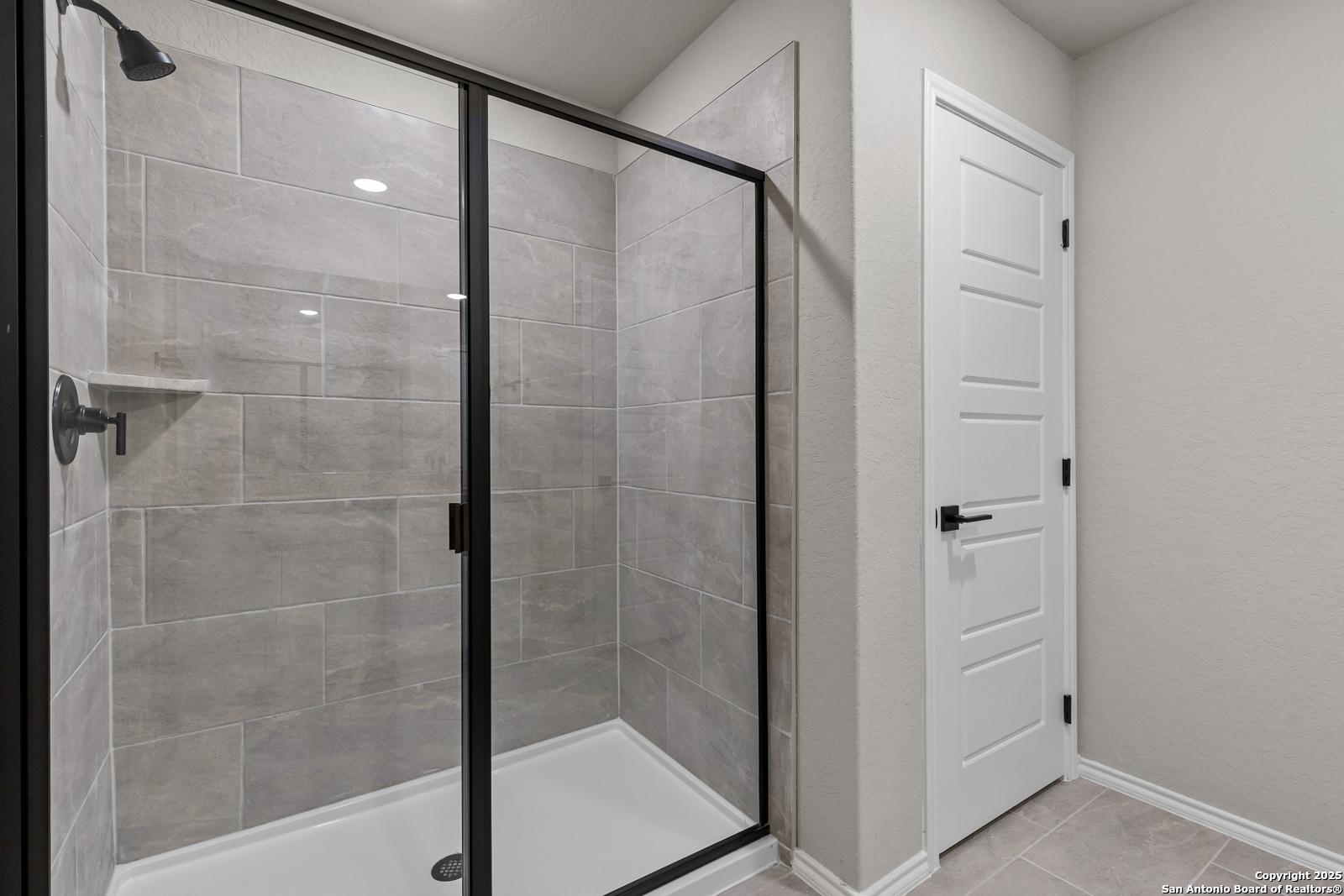 Modern frameless glass shower with gray subway tiles and built-in shelf in master bath of Davidson Homes The Murray I, San Antonio, TX
