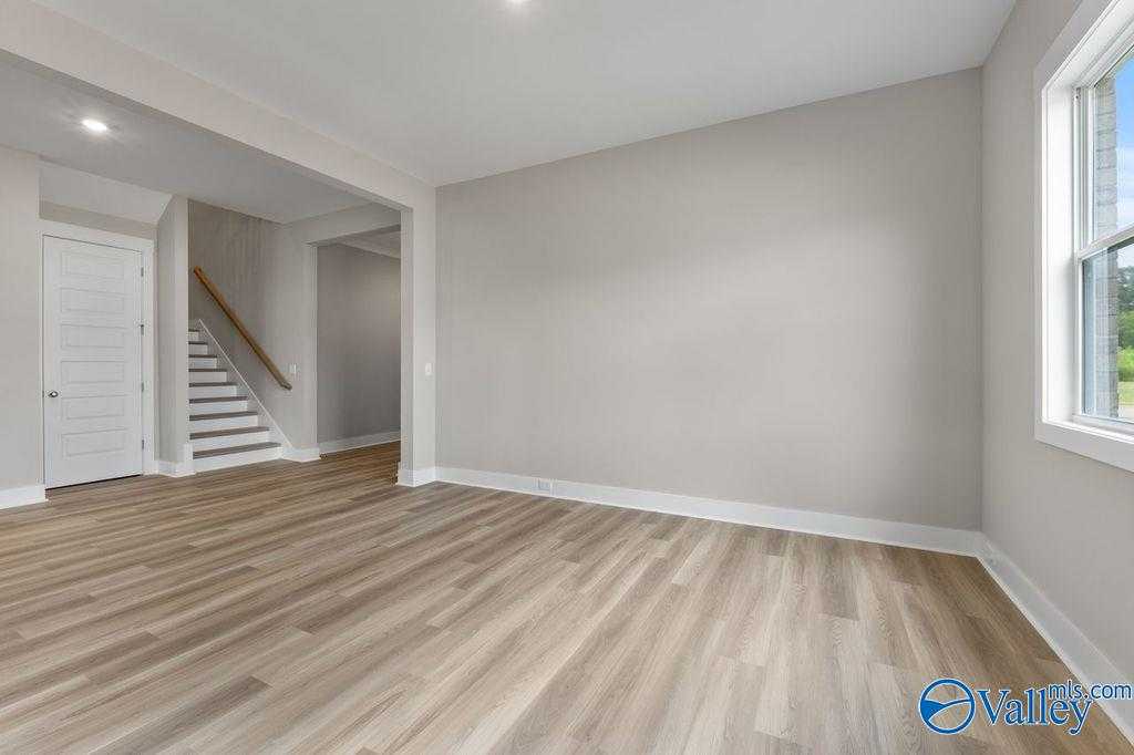 Spacious foyer with light oak floors, wooden staircase, and neutral walls in Evermore Homes The Oxford, Owens Cross Roads, AL