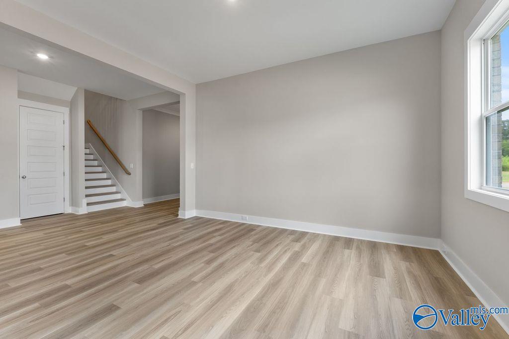 Spacious foyer with light oak floors, wooden staircase, and neutral walls in Evermore Homes The Oxford, Owens Cross Roads, AL