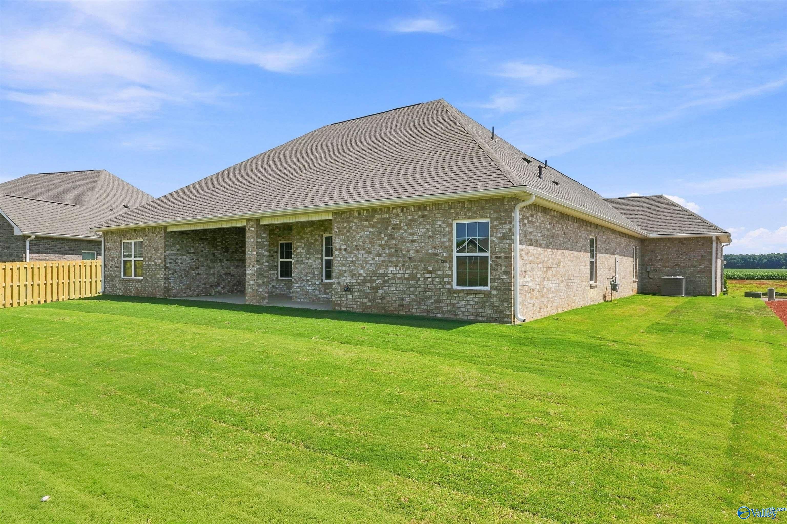 Rear exterior view of a brick home with a covered patio and spacious backyard in Kendall Farms, Toney, Alabama.