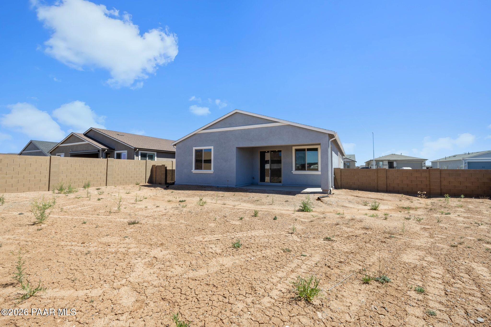 Single-story gray home exterior with large windows, fenced arid yard, and neighboring houses in North Ridge at Pronghorn Ranch, Prescott Valley, Arizona