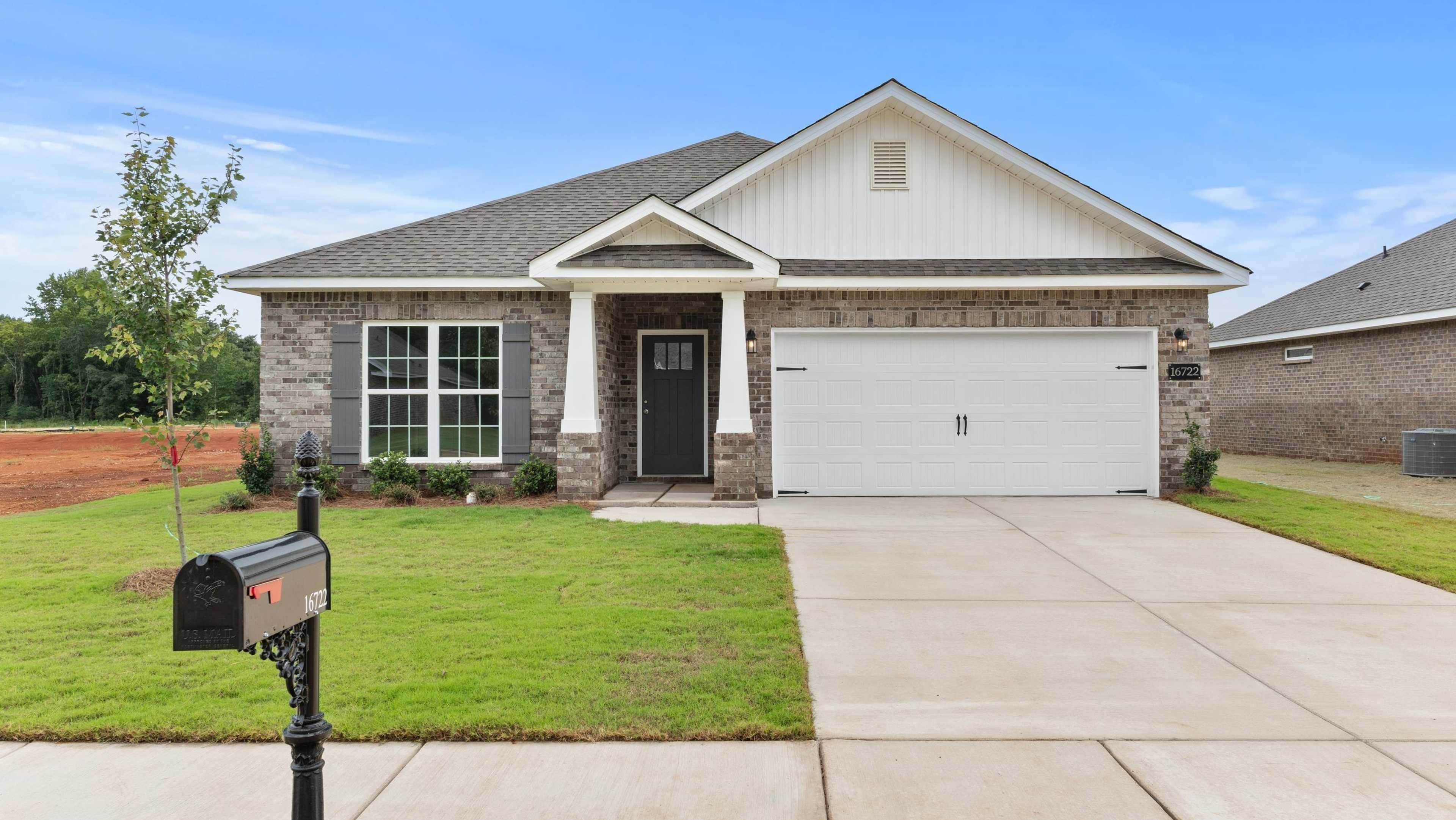 Modern gray brick ranch home with white gabled roof, covered porch, double garage, and manicured lawn at Davidson Homes open house