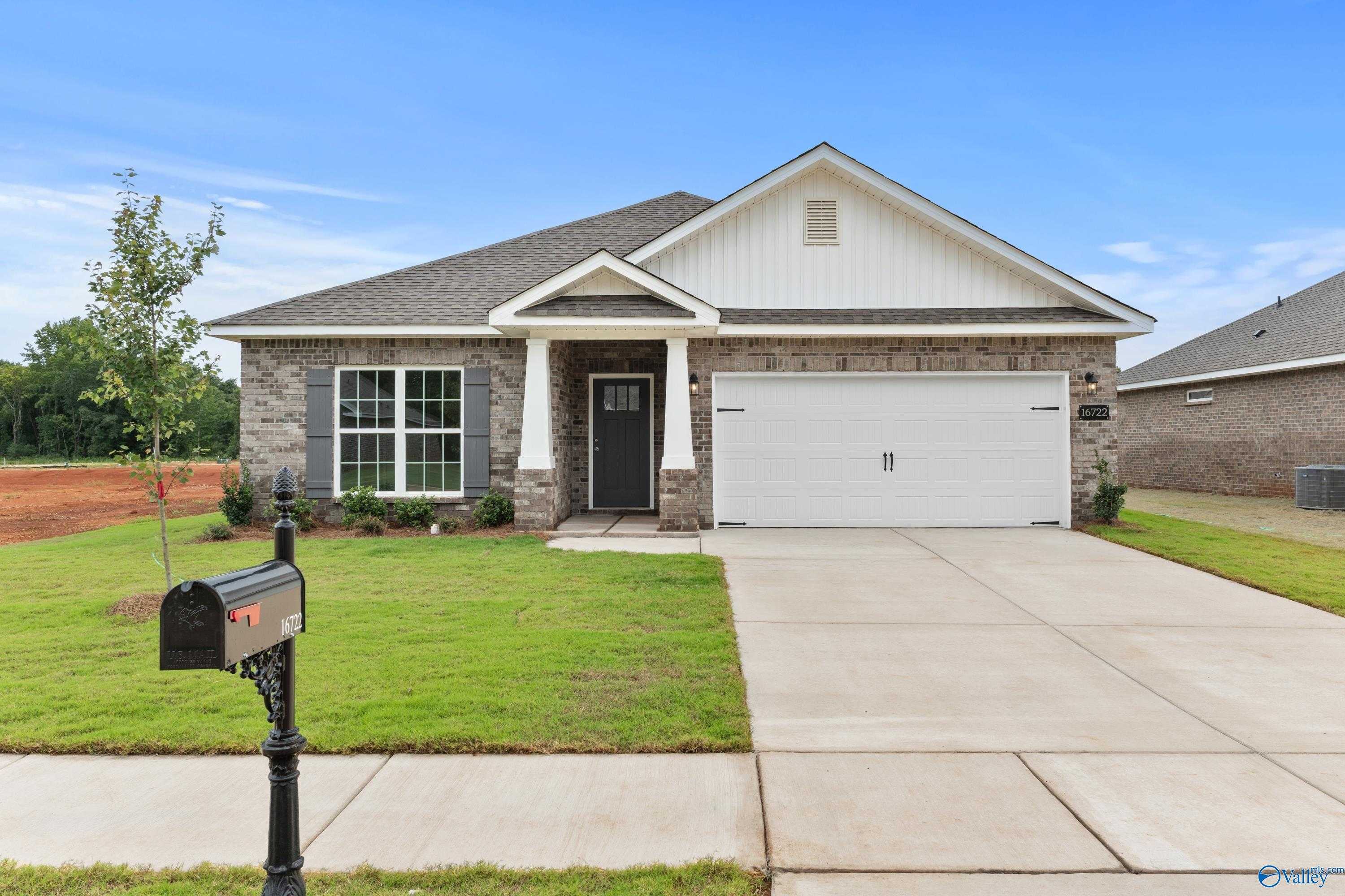 Charming stone and brick 1-story home with 2-car garage, gabled roof, and lush lawn in Ricketts Farm, Athens, Alabama