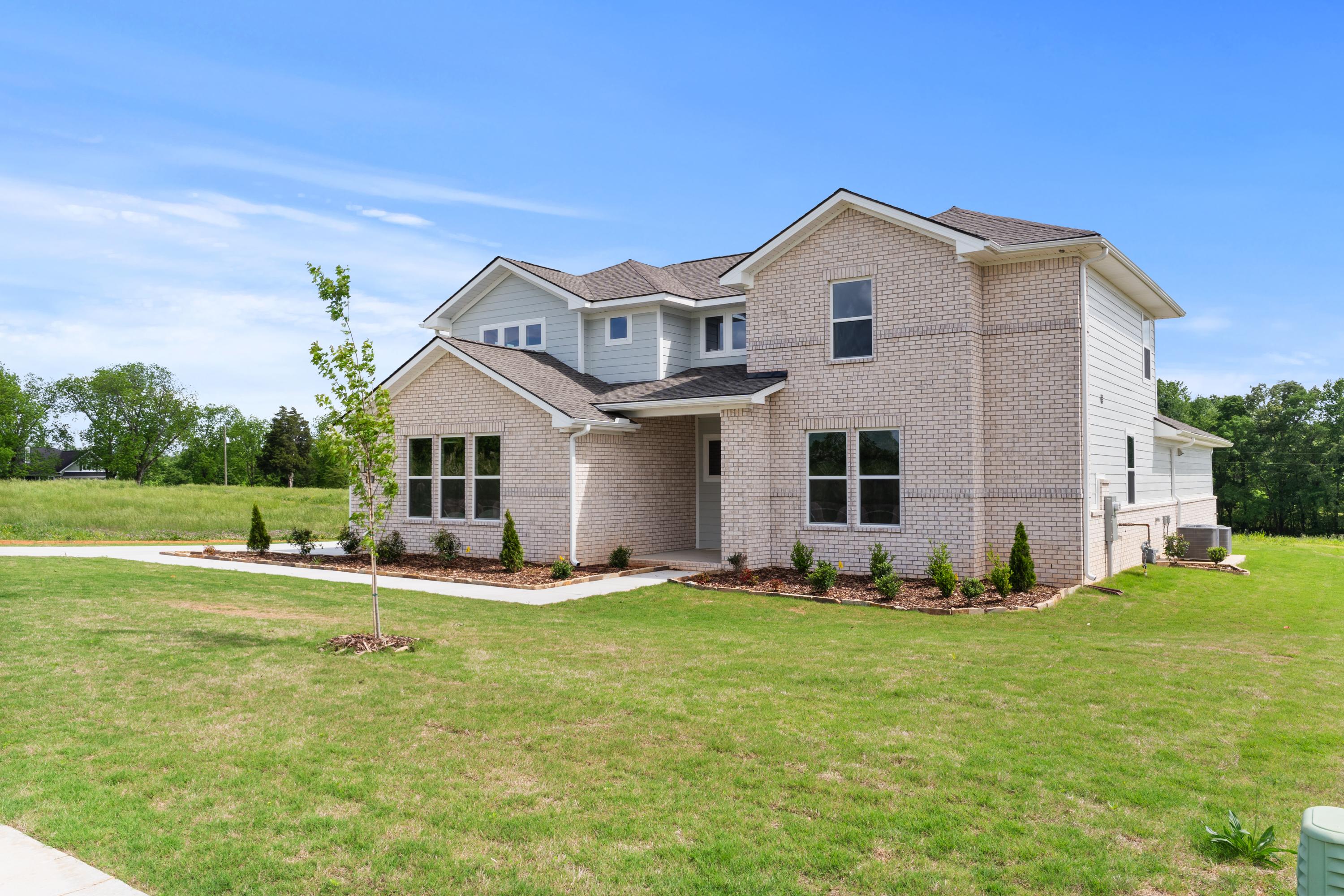 Modern single-story brick home elevation of The Haven E by Evermore Homes, featuring gabled roof, large windows, and landscaped lawn