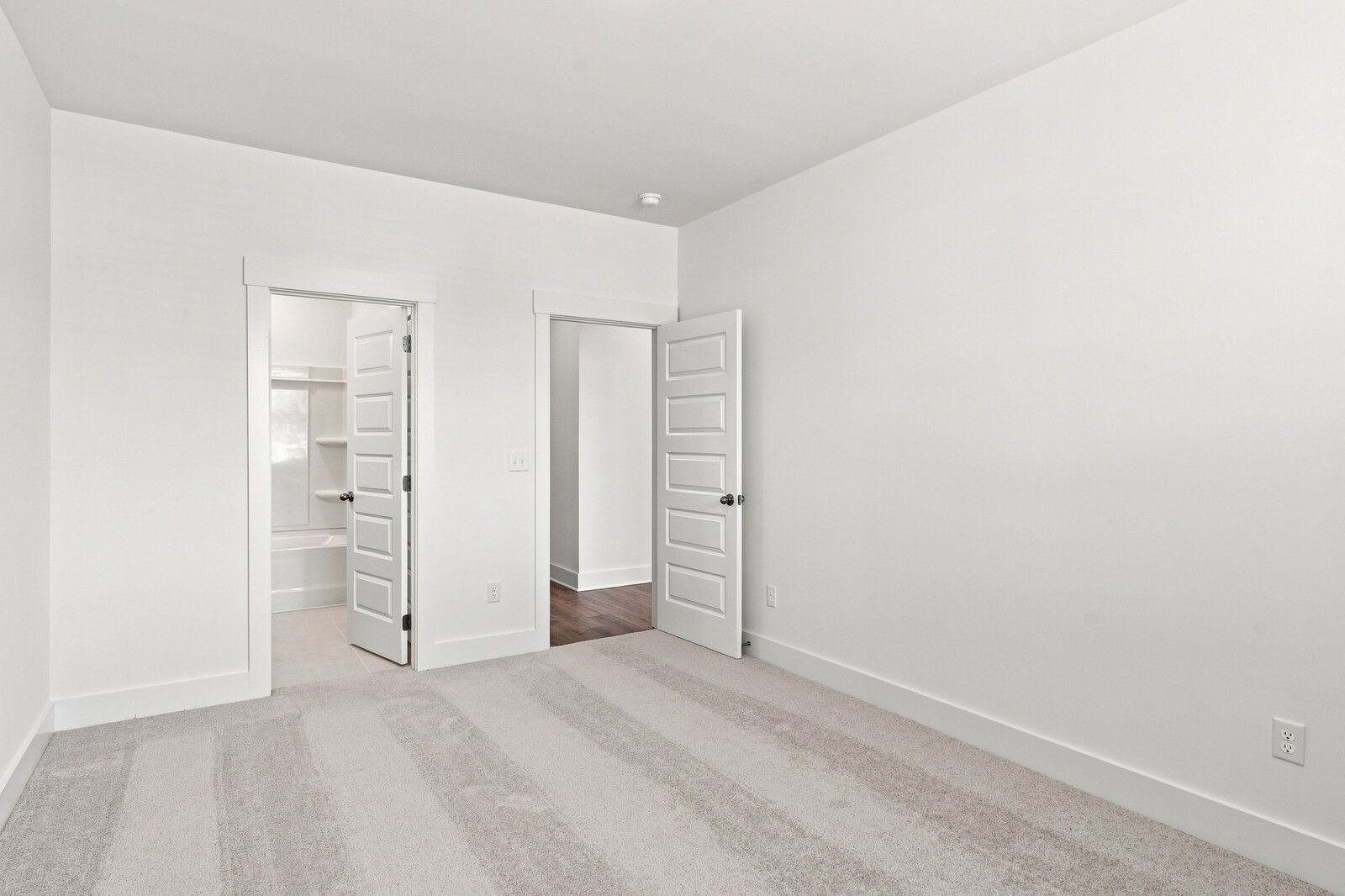 Bright carpeted bedroom with open doors to private bath and hallway in Davidson Homes The Willow C, Woods Crossing, Gallatin, TN