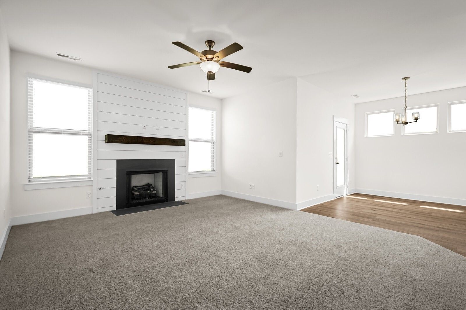 Living room with shiplap fireplace and carpet in The Ash A floor plan at Woods Crossing, Gallatin, Tennessee.