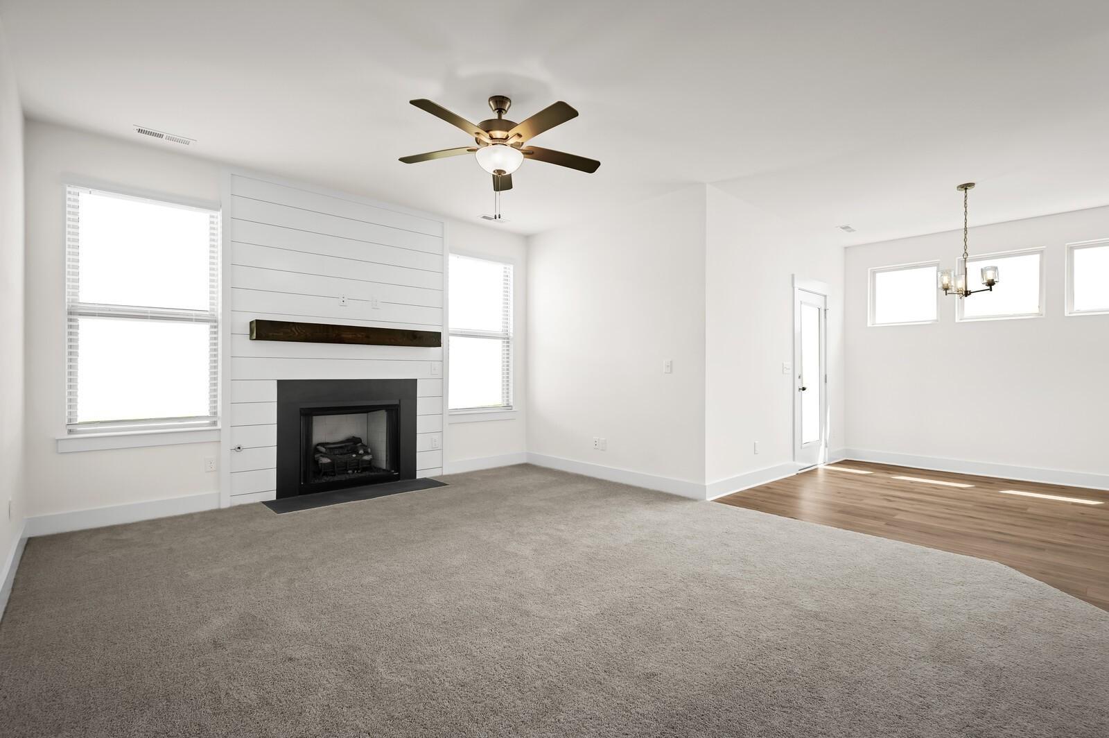 Living room with shiplap fireplace and carpet in The Ash A floor plan at Woods Crossing, Gallatin, Tennessee.