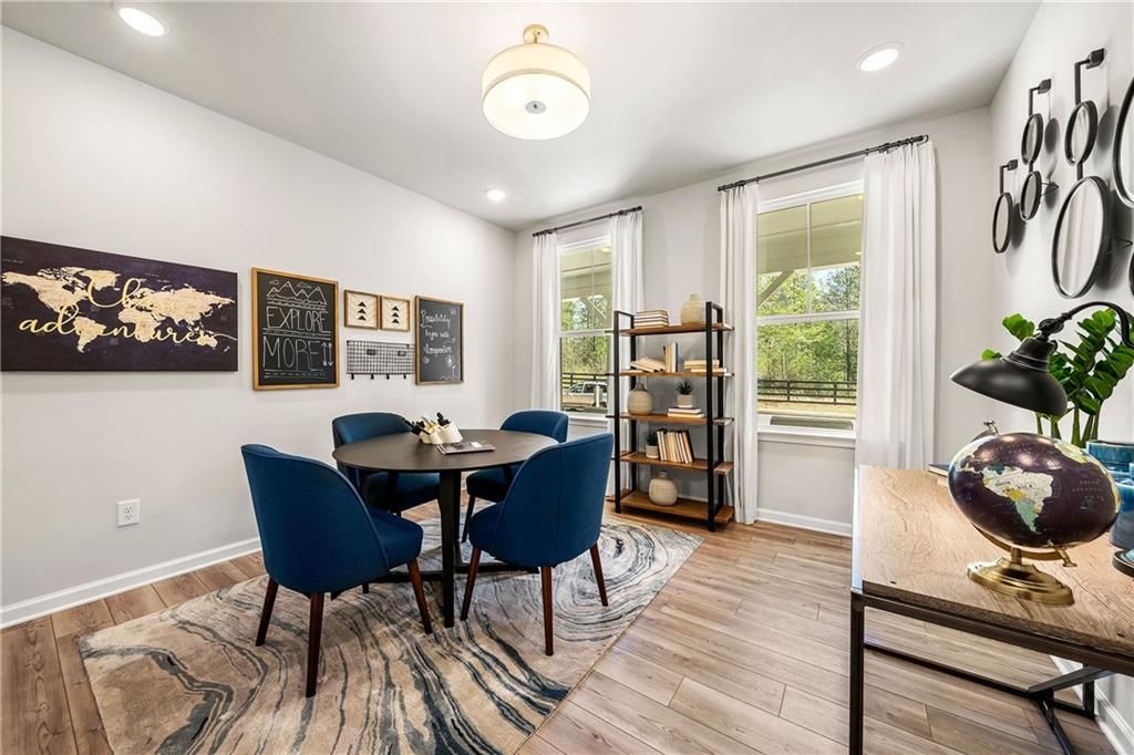 Cozy dining nook with round black table, blue velvet chairs, world map art, and bookshelf in Davidson Homes The Willow B, Dallas, Georgia