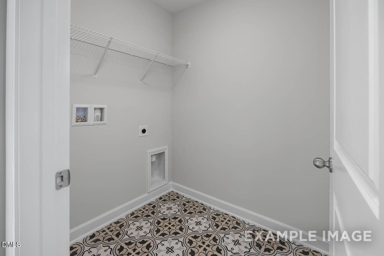 Bright laundry room with open shelving, utility sink, and patterned tile floor in Davidson Homes The Adalynn A, Lillington, NC