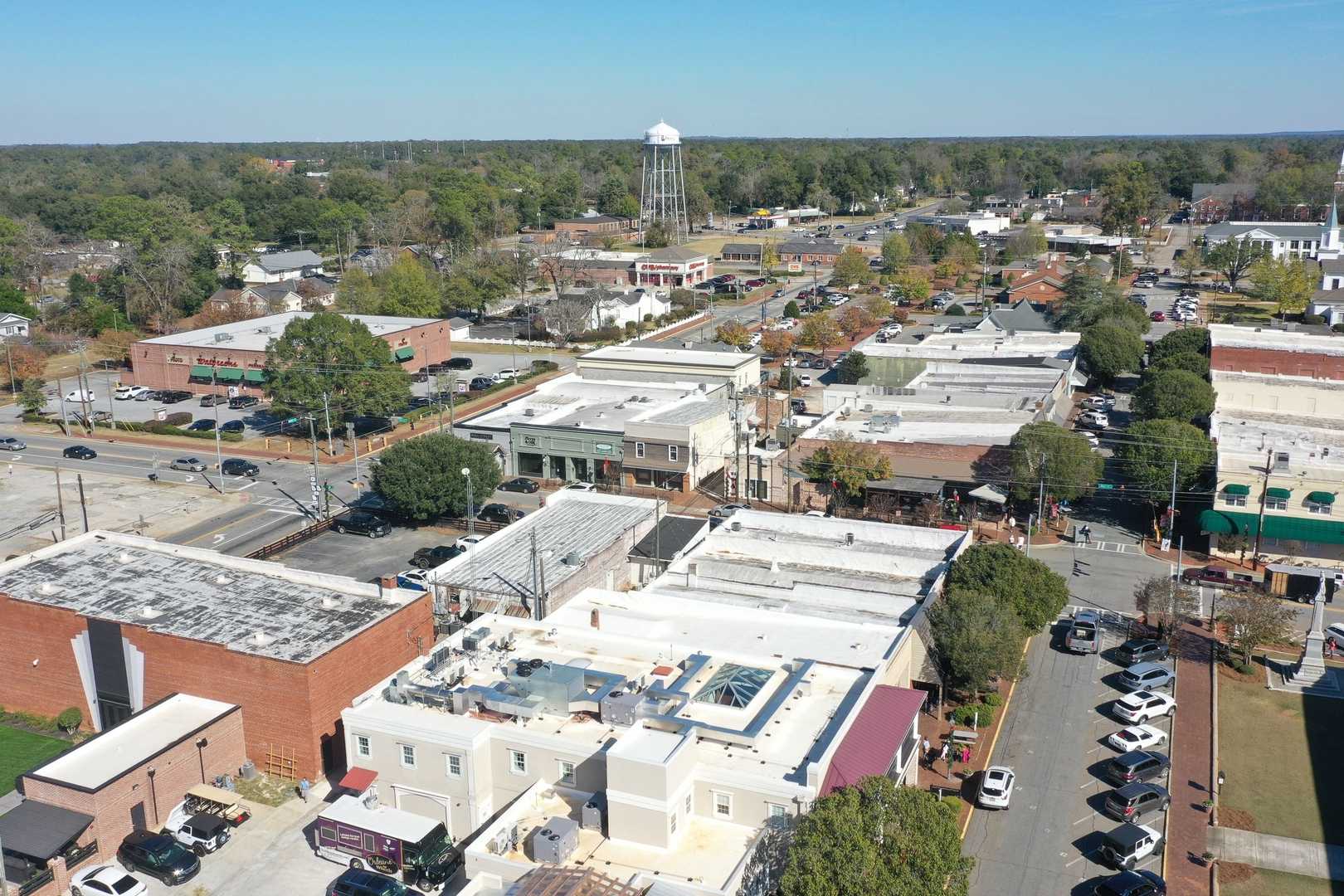 Aerial view of downtown Perry Georgia near Ivy Glen featuring historic brick buildings, tree-lined streets, and water tower