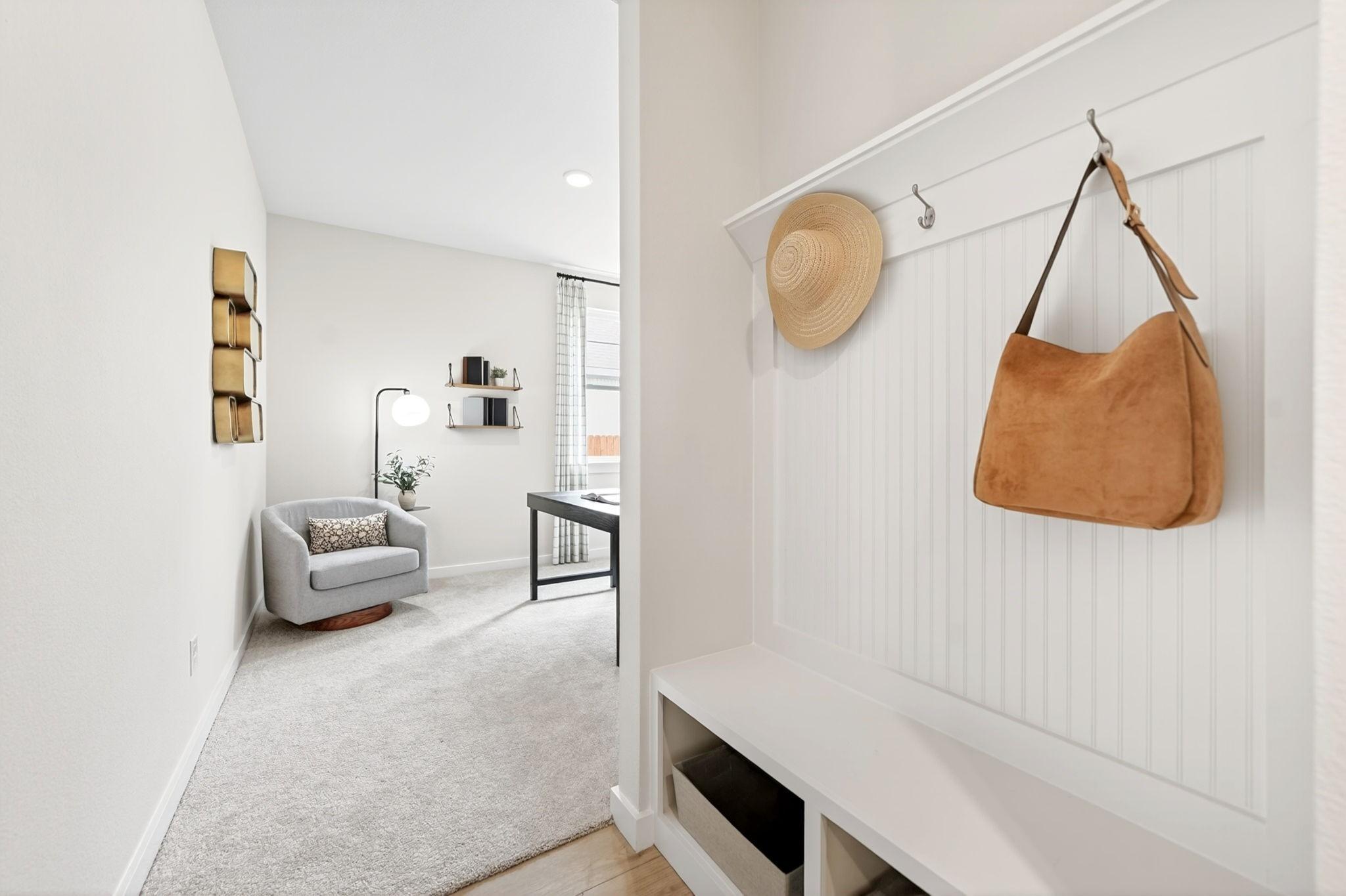 White mudroom bench with hooks leading into a cozy home office in The Laurel M floor plan at Parks at Foster Crossing.