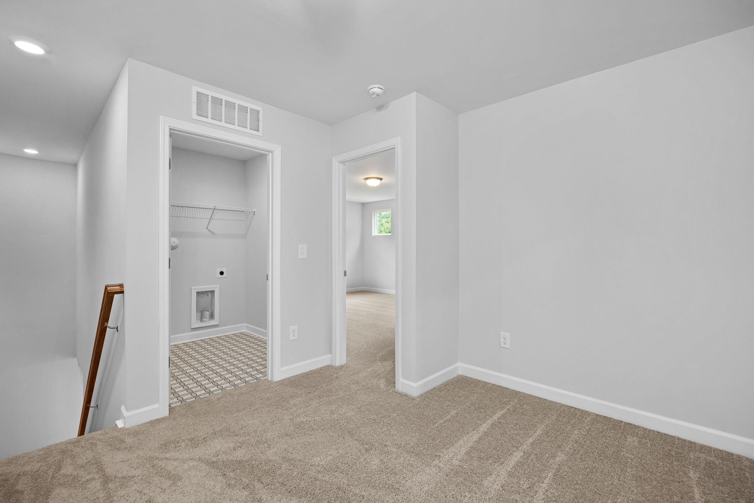 Upper floor landing in The Durham featuring a convenient laundry closet and carpeted hallway in Lillington, NC.