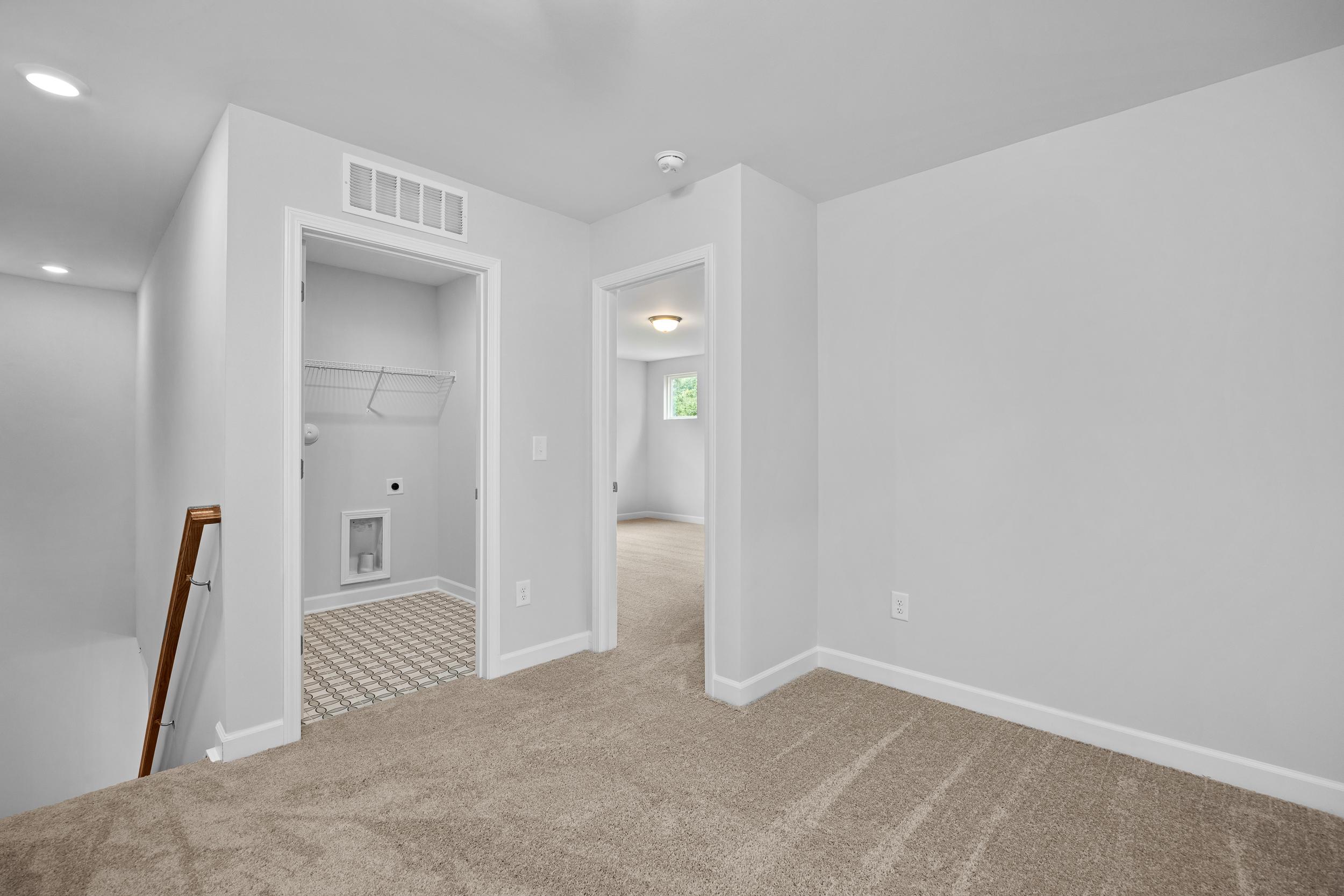Upper floor landing in The Durham featuring a convenient laundry closet and carpeted hallway in Lillington, NC.