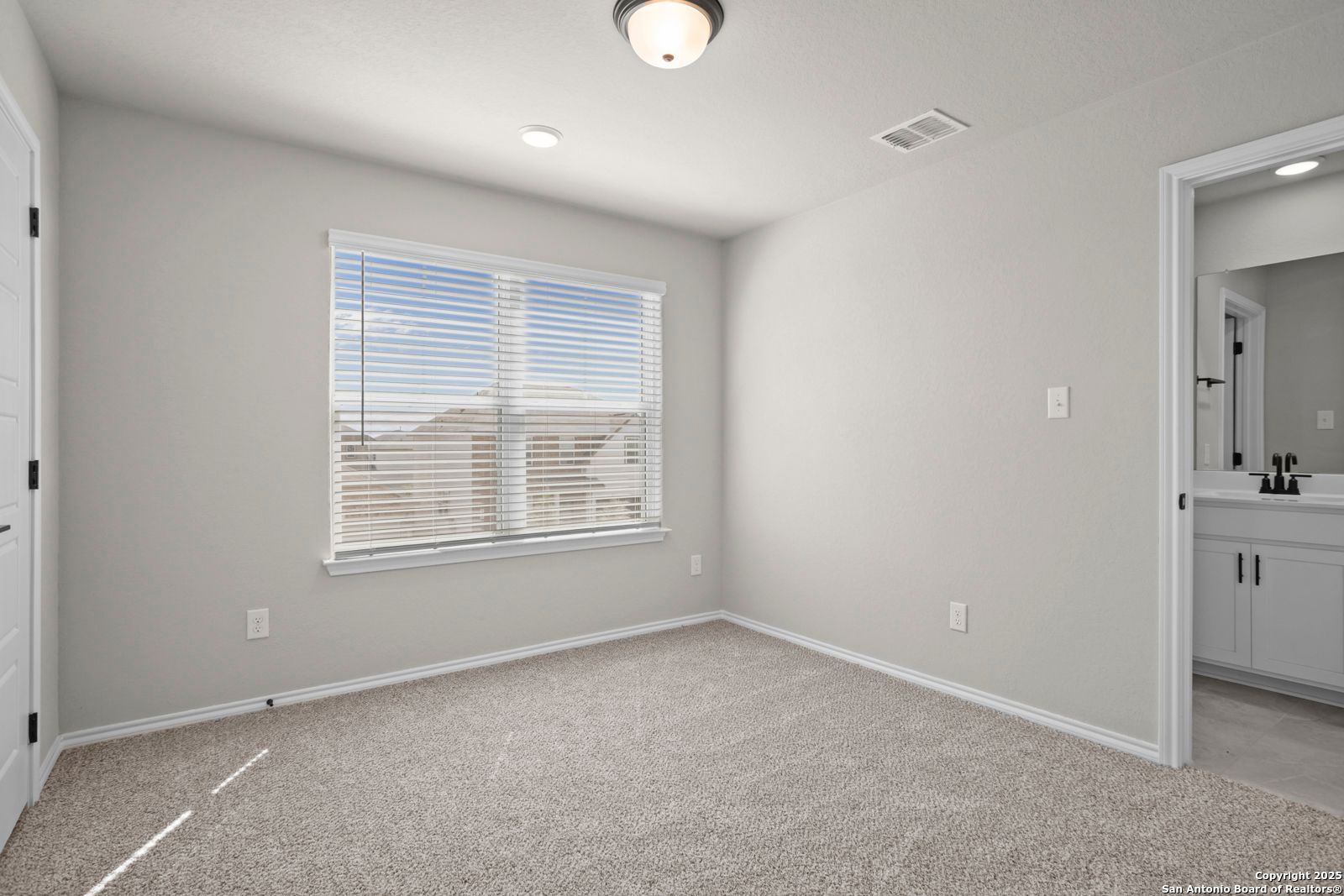Bright secondary bedroom with gray walls, beige carpet, window blinds, and en-suite bath in Davidson Homes The Sequoia A, Converse, Texas