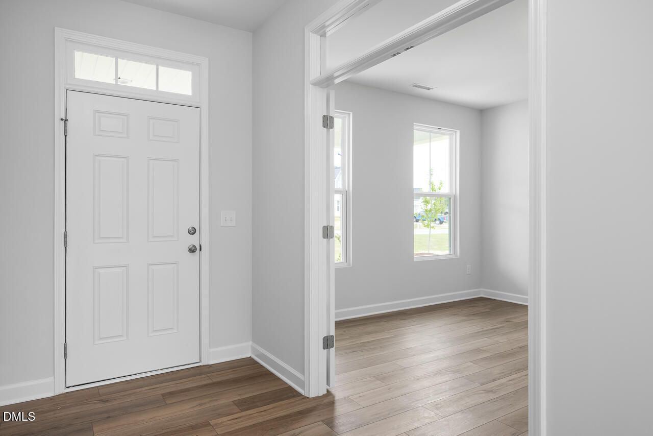 Bright entryway with white front door, gray walls, hardwood floors in Davidson Homes The Hickory II B, Zebulon, NC