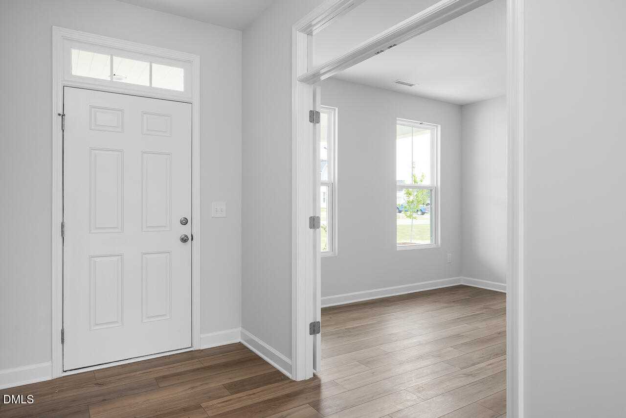 Bright entryway with white front door, gray walls, hardwood floors in Davidson Homes The Hickory II B, Zebulon, NC