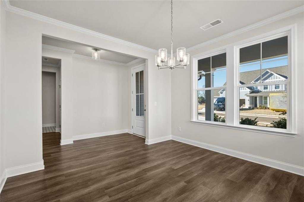 Bright dining room with hardwood floors, crystal chandelier, and large windows to neighborhood in Davidson Homes The Ash C at Wehunt Meadows, Hoschton