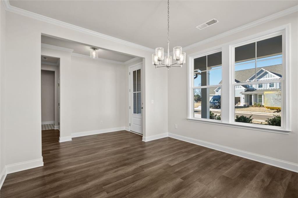 Bright dining room with hardwood floors, crystal chandelier, and large windows to neighborhood in Davidson Homes The Ash C at Wehunt Meadows, Hoschton
