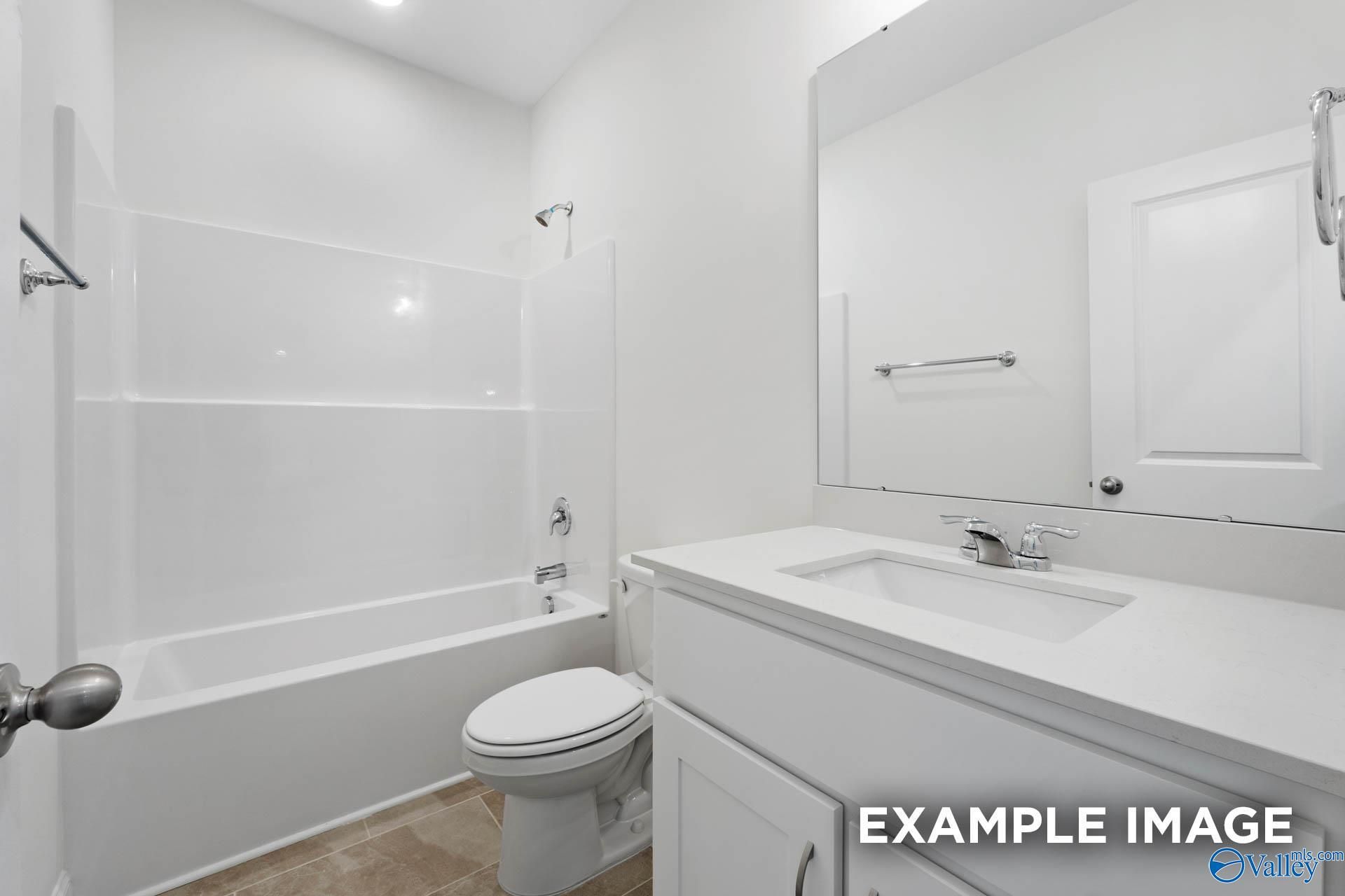 Modern white guest bathroom with tub-shower combo, vanity, and toilet in Davidson Homes The Oxford, Huntsville, Alabama