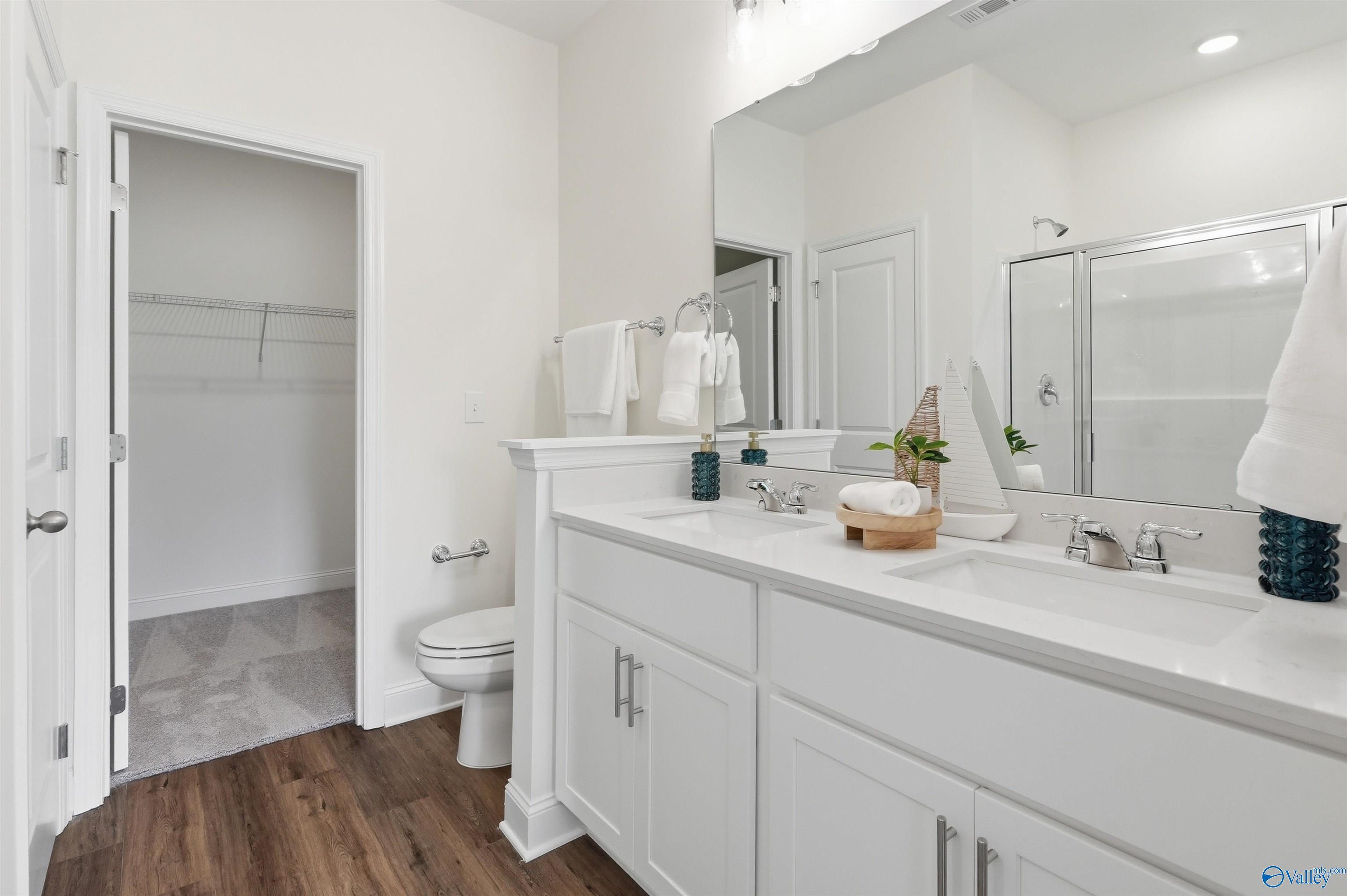 Modern primary bathroom with dual vanity, white cabinetry, and walk-in closet in The Franklin C home, Meridianville, AL.
