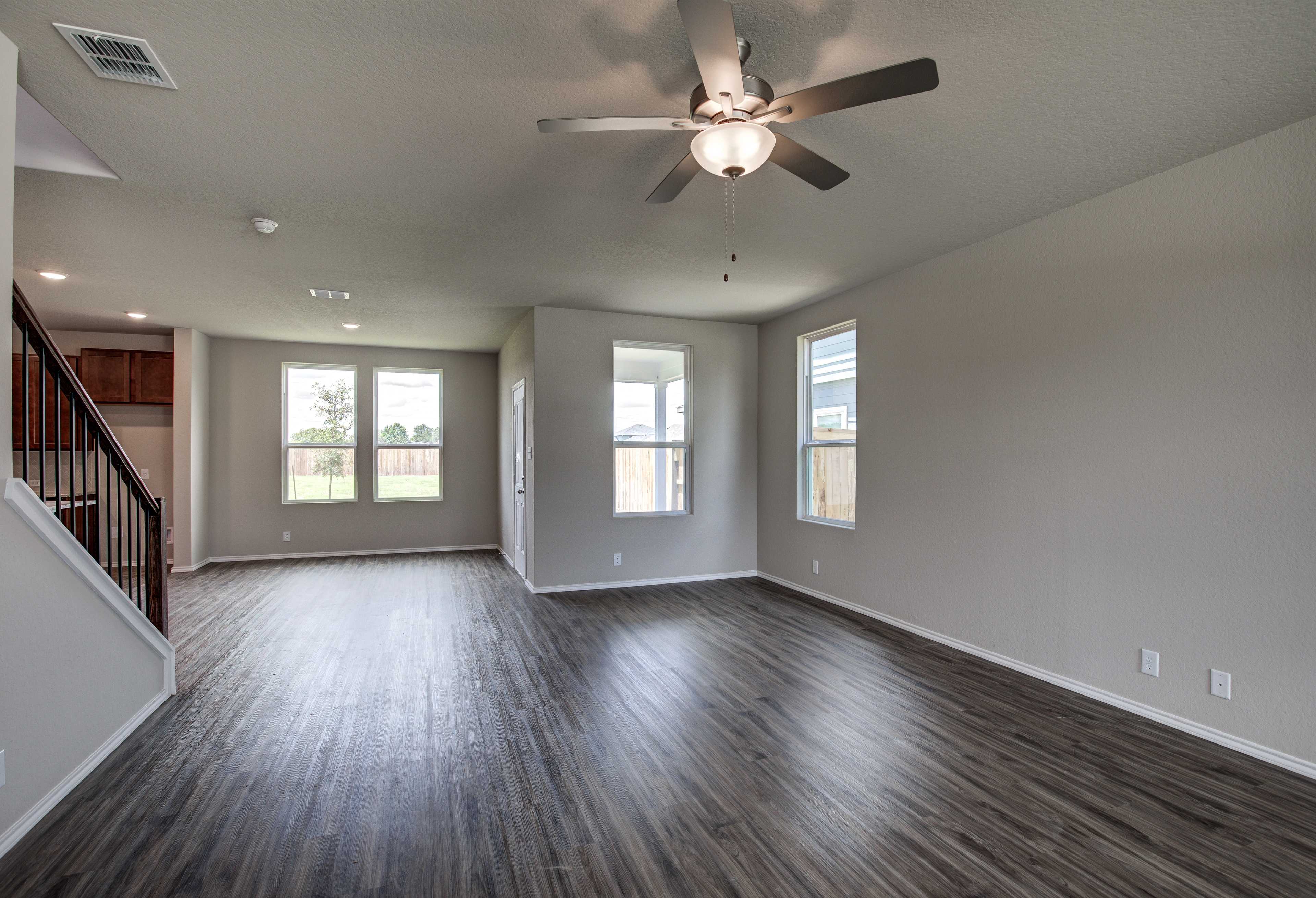 Spacious open-concept living area in The Murray floor plan with hardwood floors, ceiling fan, and large windows