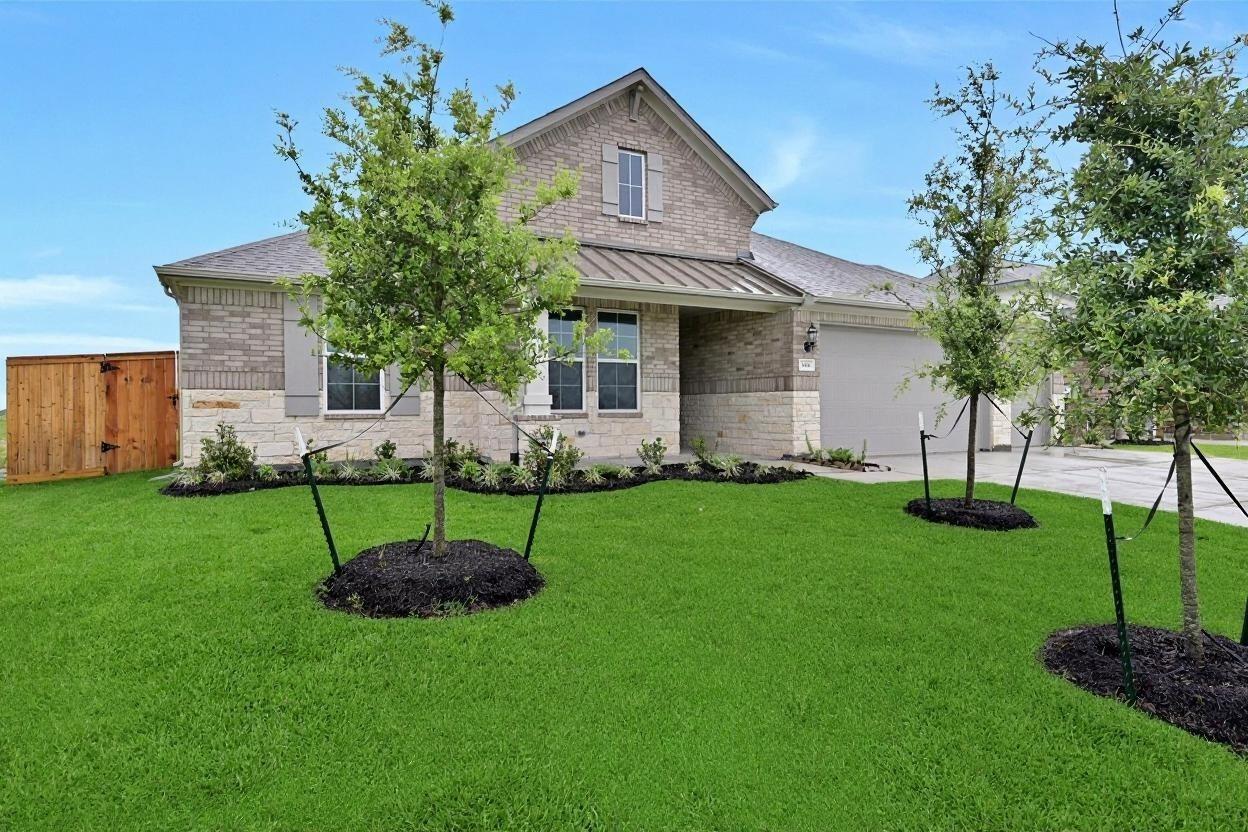 Modern beige brick single-story home with 3-car garage, manicured green lawn, and young trees in Lago Mar, Texas City