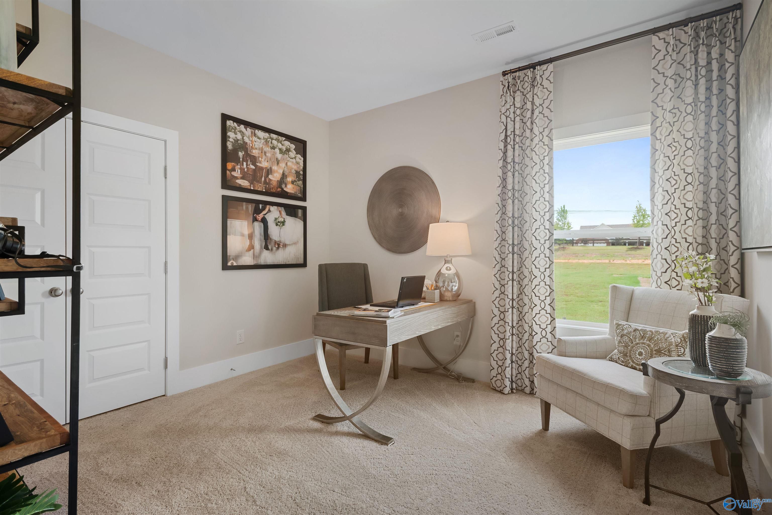 Cozy home office with sleek desk, laptop, armchair, and window view of green lawn in Davidson Homes The Everett, New Market, Alabama