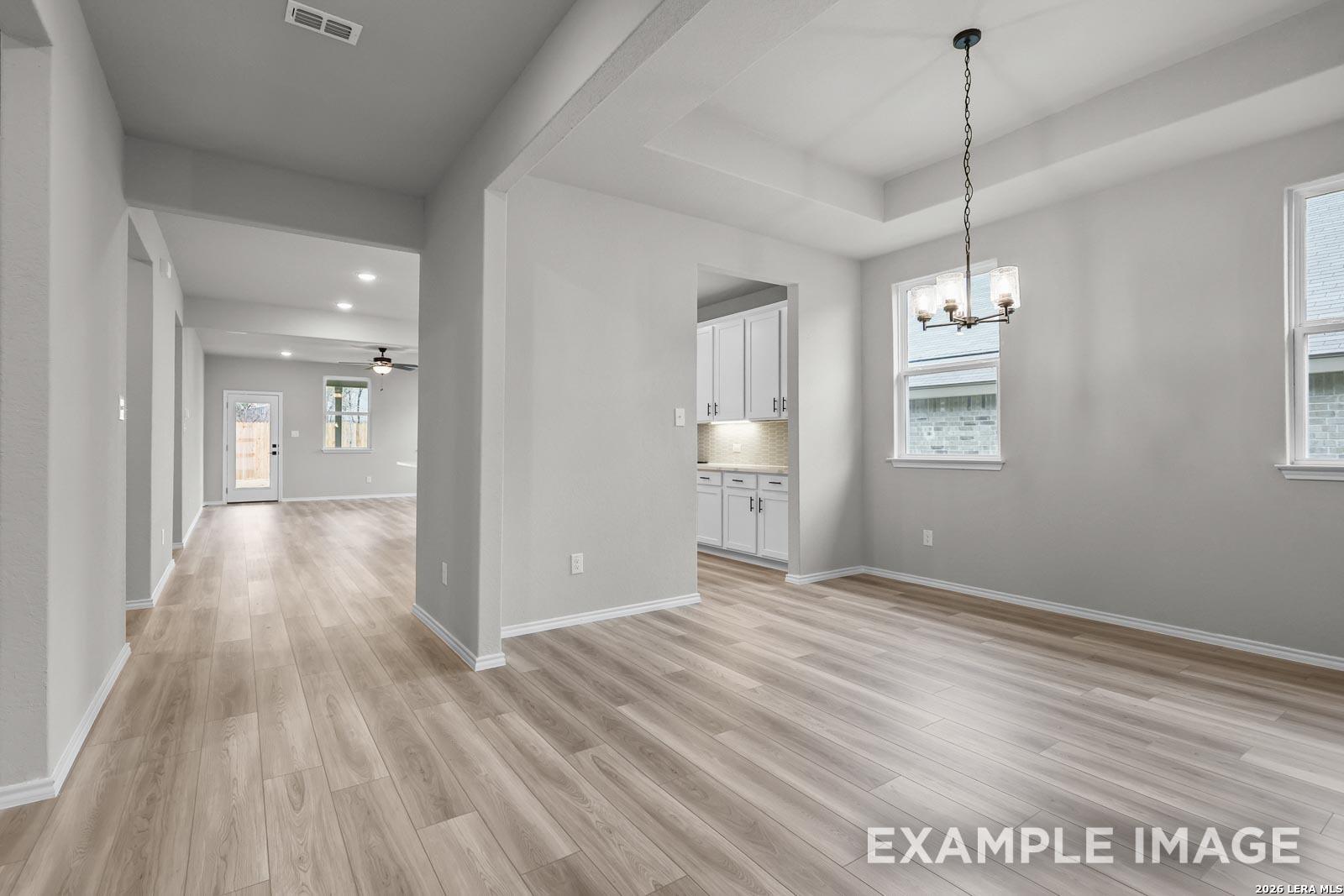 Bright dining area with tray ceiling and wood-plank flooring in The Glenwood E floor plan, Royal Crest, San Antonio.