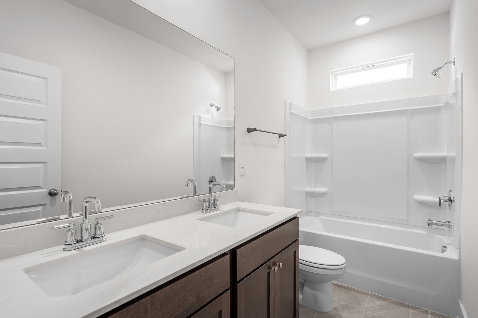 Modern bathroom in The Cottonwood featuring a dual-sink vanity, dark cabinetry, and a clean white tub and shower combo.