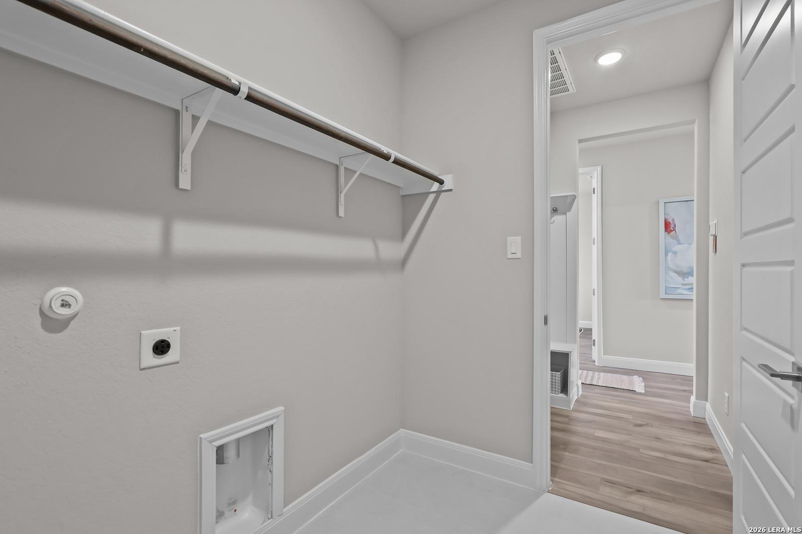 Modern laundry room with wood shelving, washer/dryer hookups, and adjacent space in Davidson Homes The Rockford G, Ladera, San Antonio