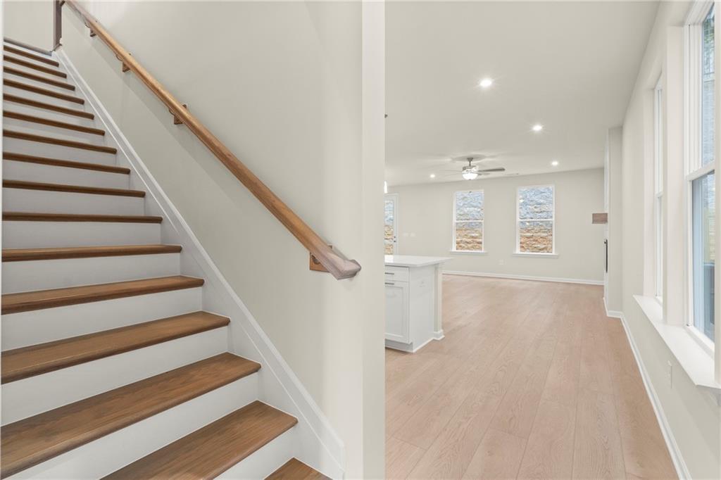 Elegant oak staircase with white railing and open upstairs hallway featuring hardwood floors in Davidson Homes The Cary A, Kennesaw, Georgia