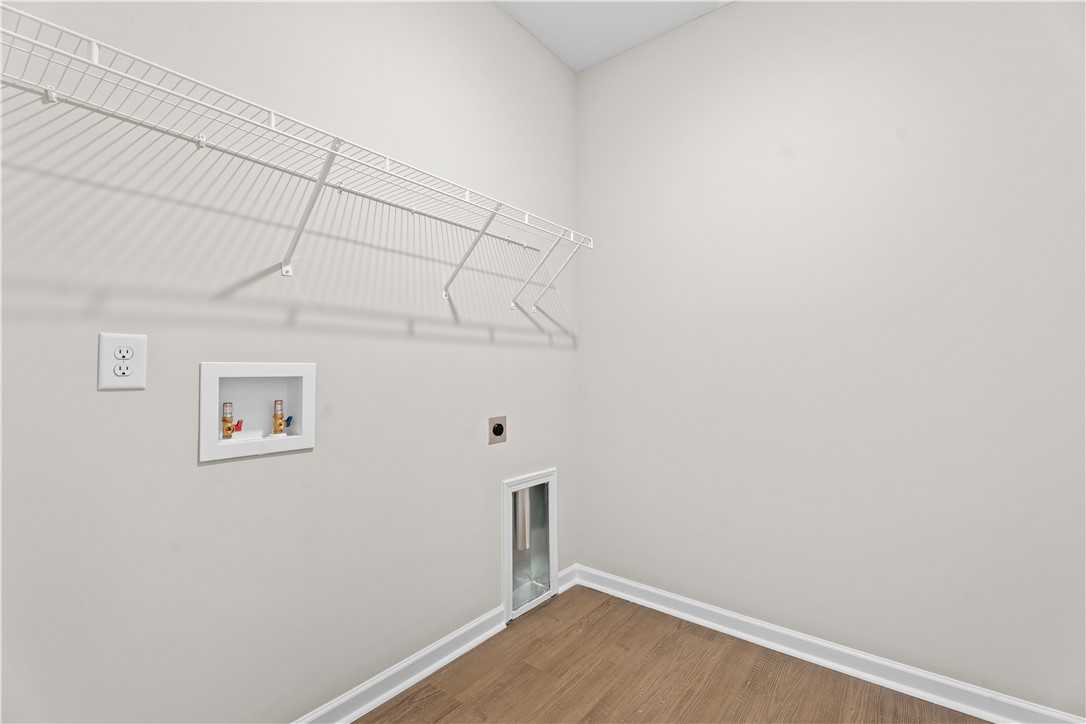 Spacious laundry room with wire shelving, washer-dryer hookups, and storage niche in Evermore Homes The Orion, Cusseta, Alabama