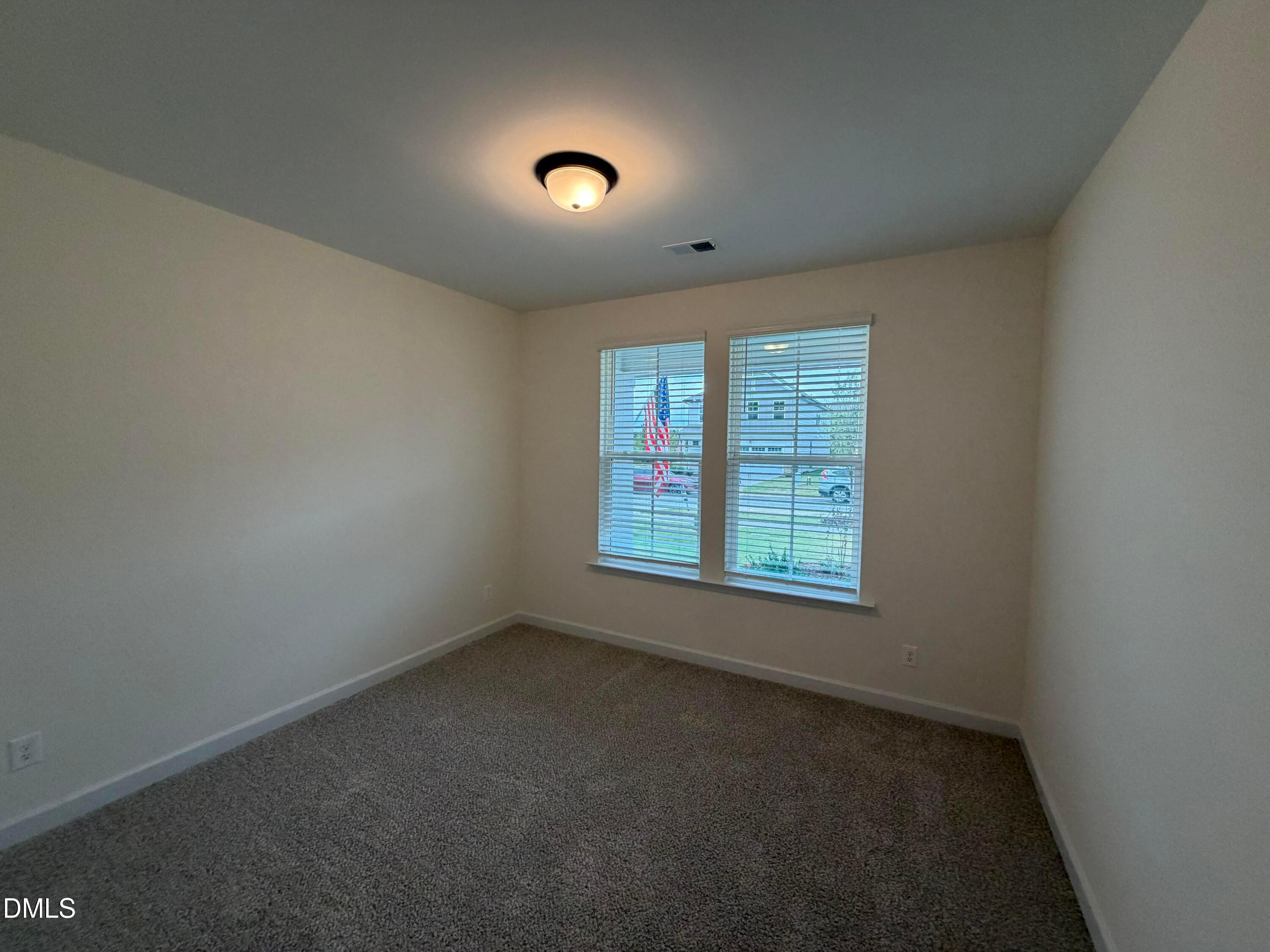 Bright empty bedroom with new carpet, neutral walls, and double windows in Davidson Homes Ashport M plan, Wendell Ridge, NC