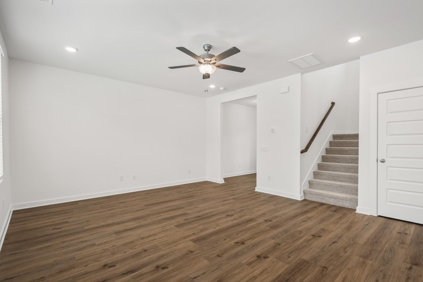 Bright entry foyer with hardwood floors, ceiling fan, and carpeted staircase in Davidson Homes The Gordon C, Sage Farms, White House, TN