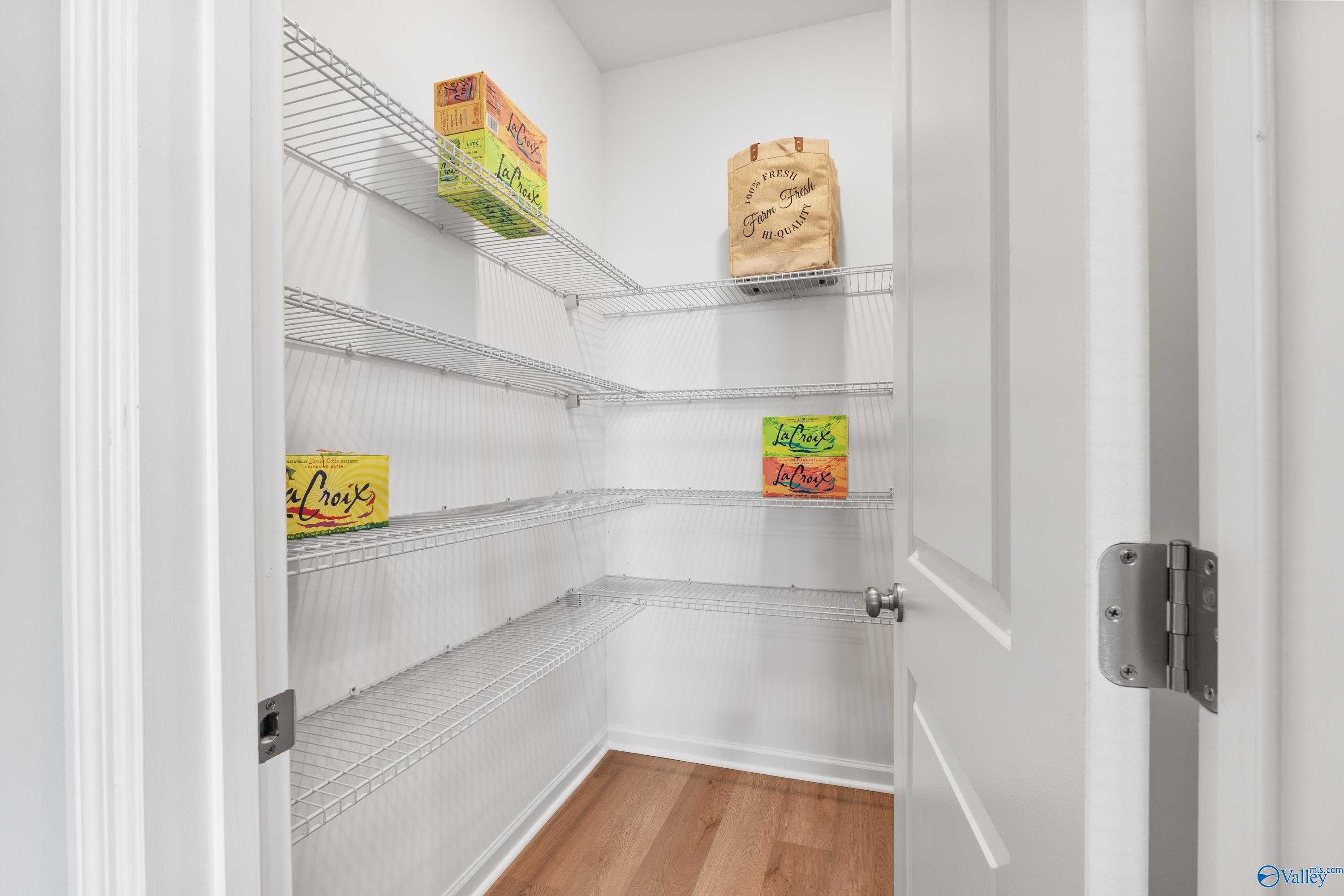 Spacious walk-in pantry with wire shelving stocked with Cheerios, Lucky Charms, and Kraft Mac & Cheese in Davidson Homes The Sanctuary, Athens, Alabama