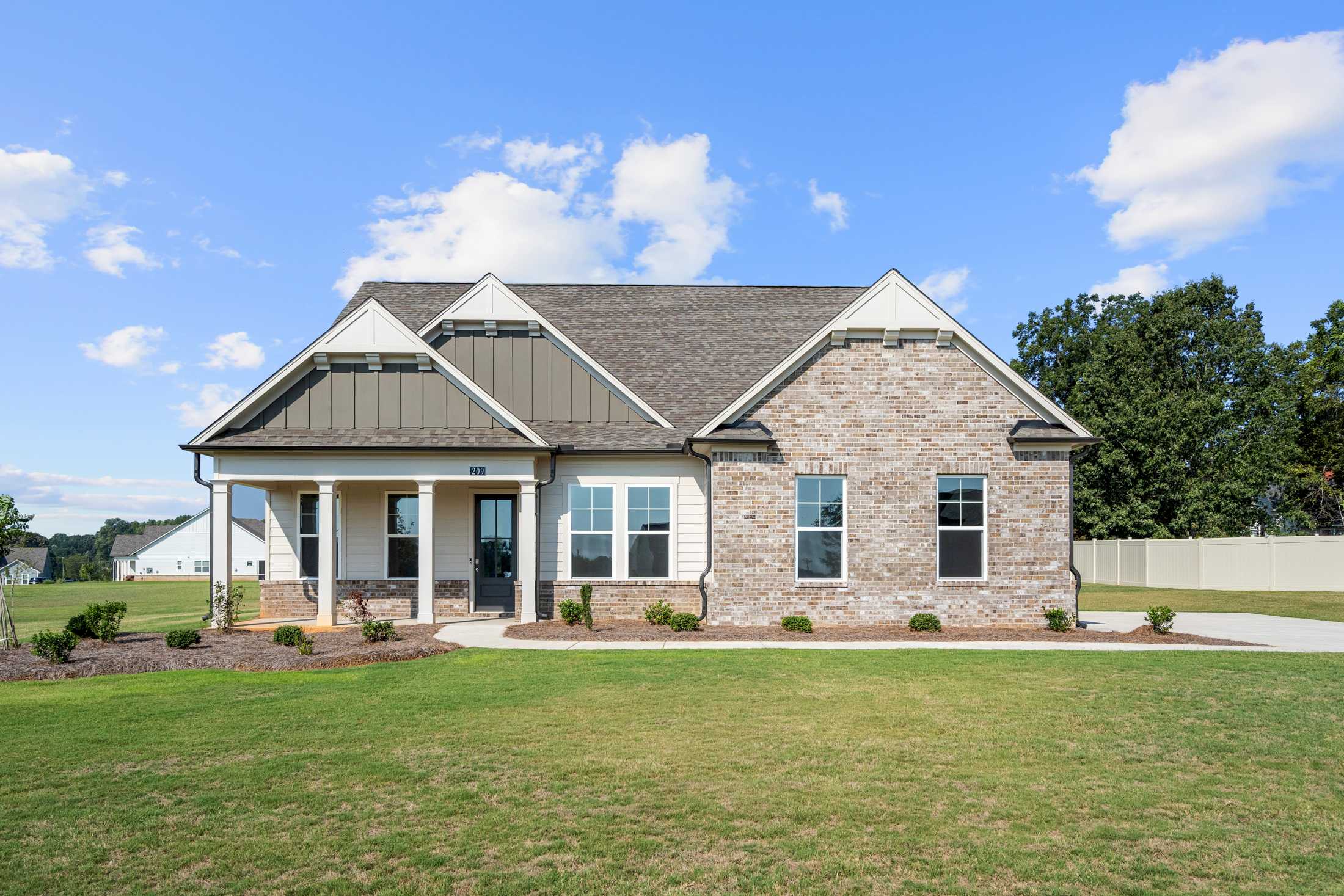 Brick ranch home exterior at The Everleigh in Locust Grove GA with covered front porch, brick siding, and landscaped yard