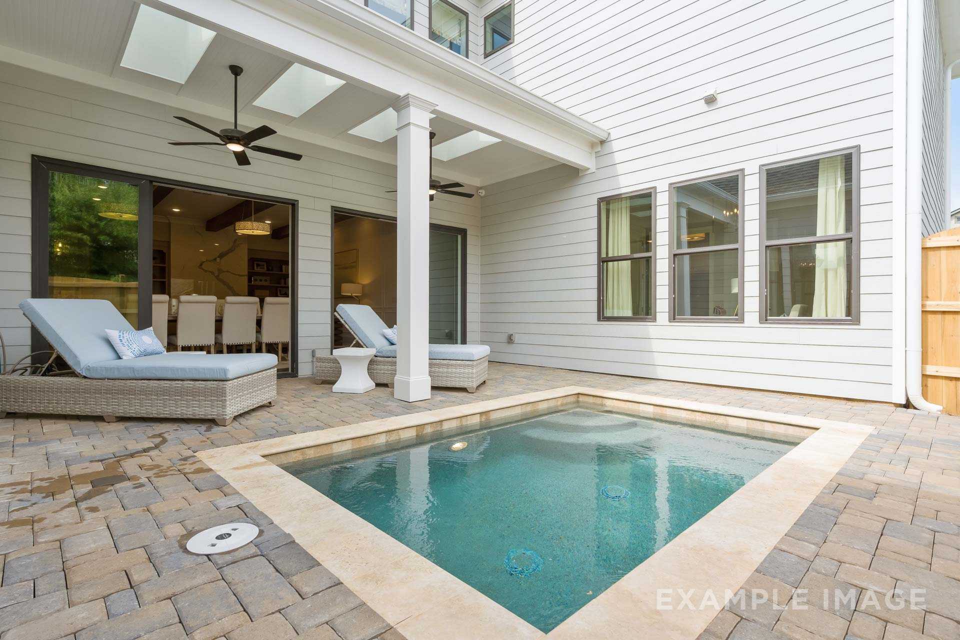 Covered patio with ceiling fans, turquoise spool, wicker lounge chairs on paver deck in The Seaside home design