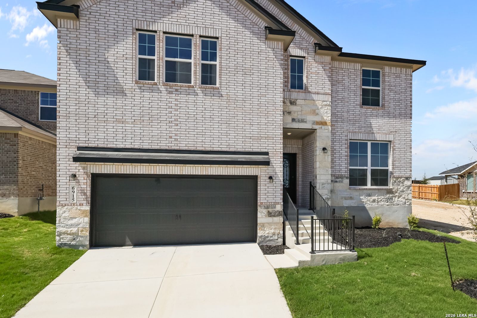 Two-story brick home with 2-car garage, concrete driveway, and green lawn in Comanche Ridge, San Antonio, Texas - Davidson Homes Sequoia B