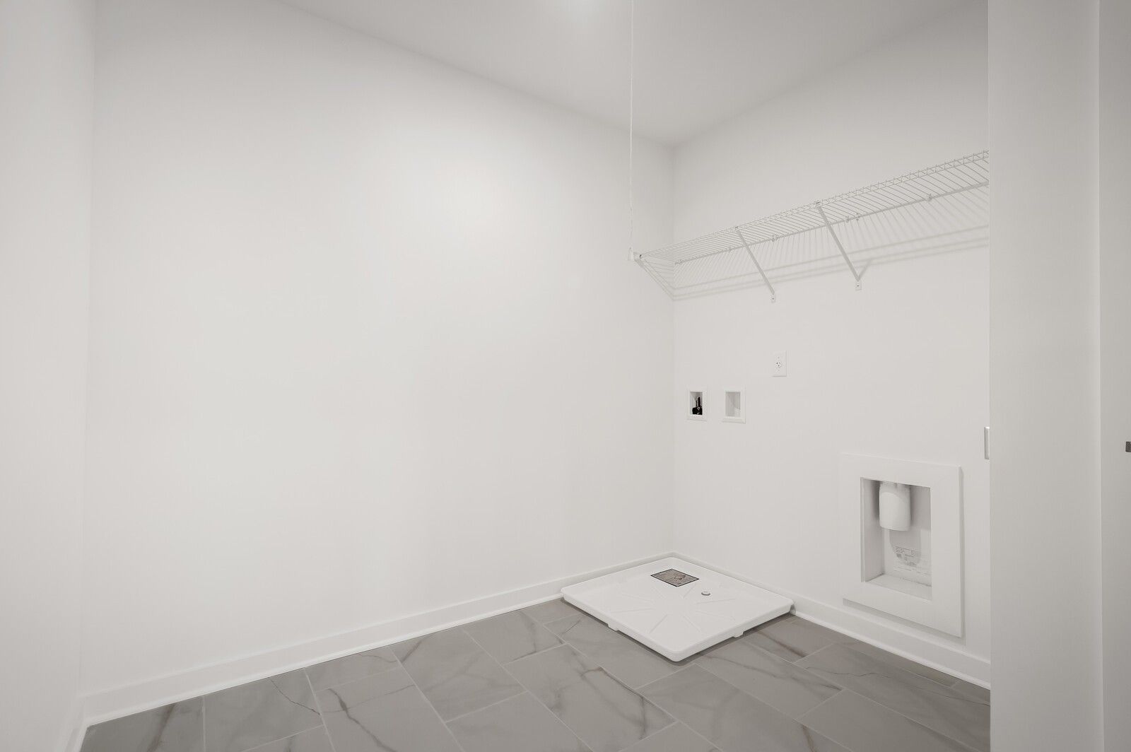 Bright laundry room with wire shelving and tiled floors in The Logan C floor plan at Calista Farms, White House, Tennessee.
