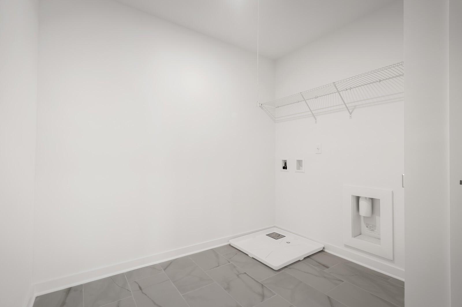 Bright laundry room with wire shelving and tiled floors in The Logan C floor plan at Calista Farms, White House, Tennessee.