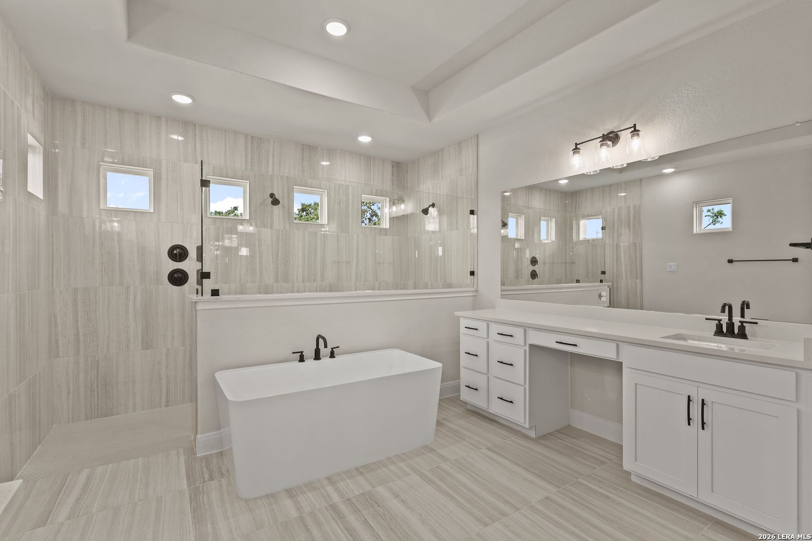 Modern primary bathroom with freestanding soaking tub and walk-in glass shower in The Summerlin B home, Potranco Oaks.