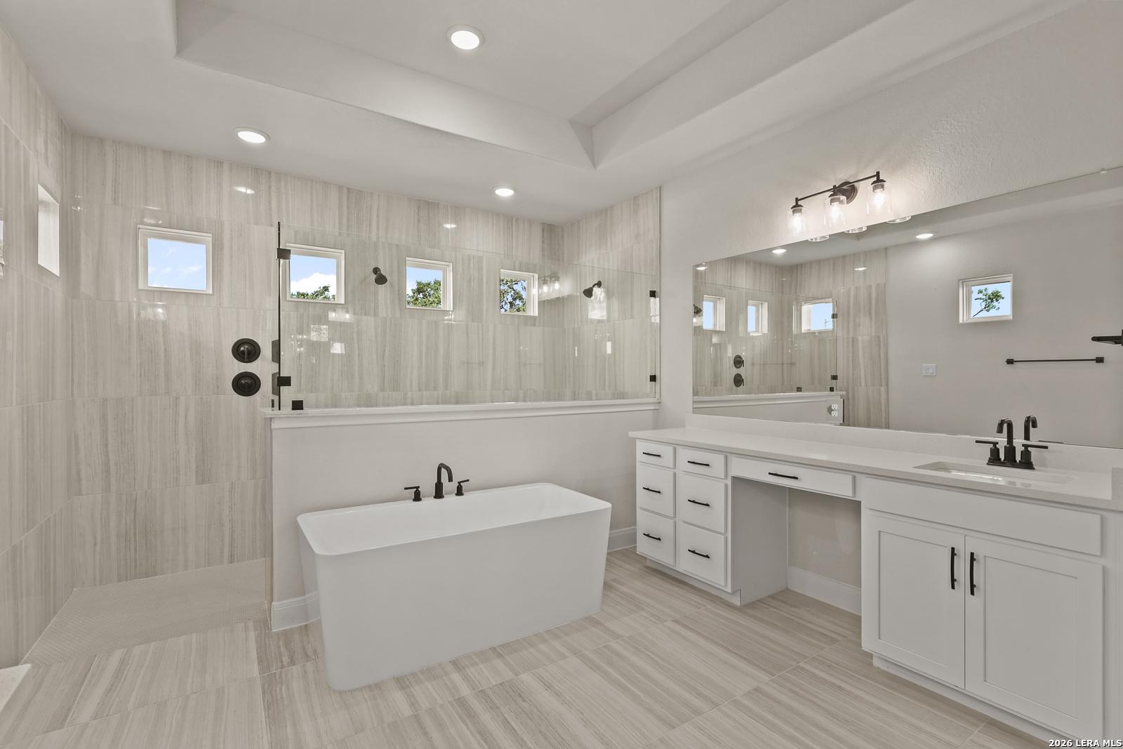 Modern primary bathroom with freestanding soaking tub and walk-in glass shower in The Summerlin B home, Potranco Oaks.