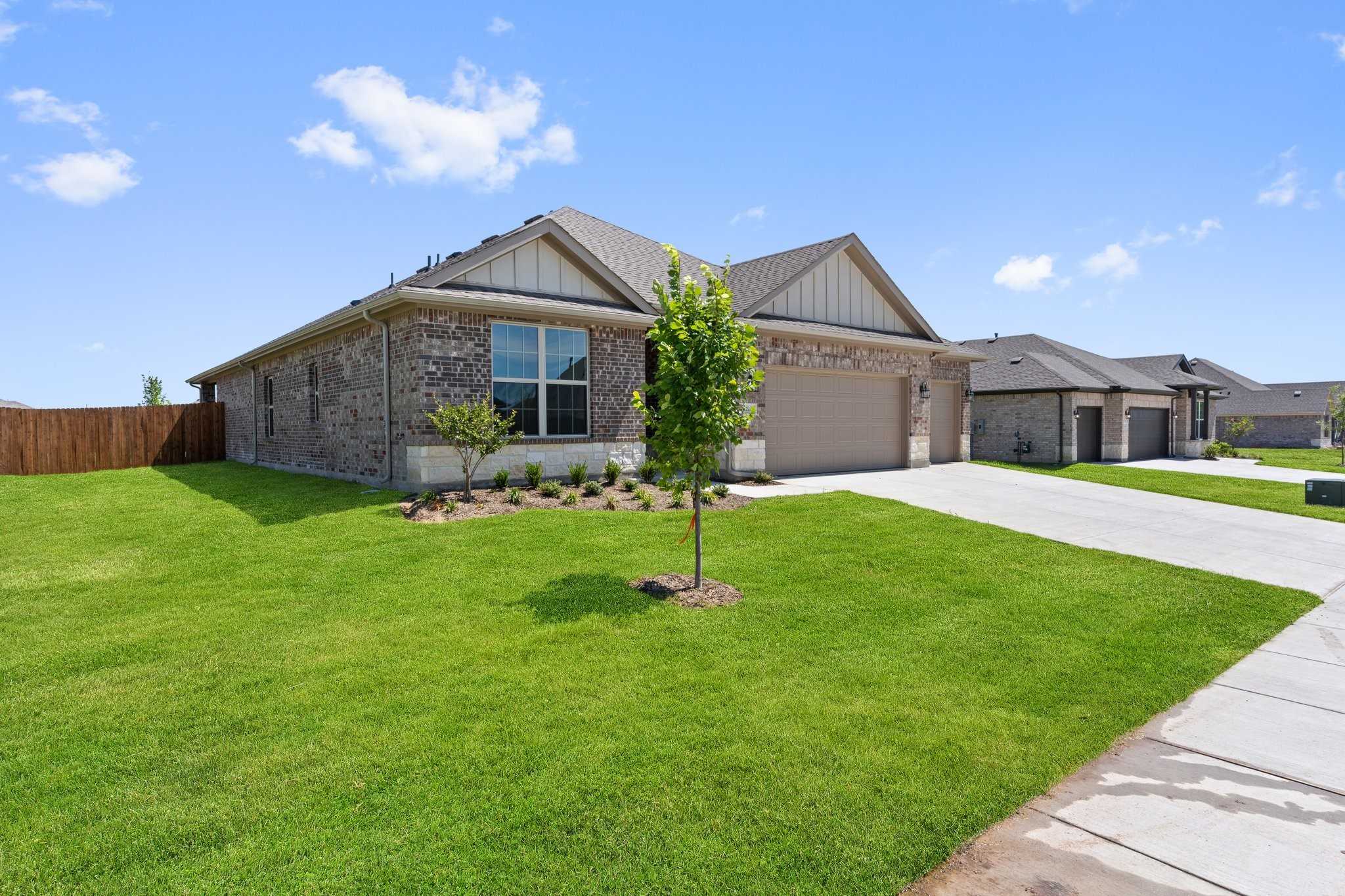 Modern 1-story brick home with 3-car garage, green lawn, and driveway in Waverly Estates, Josephine, Texas