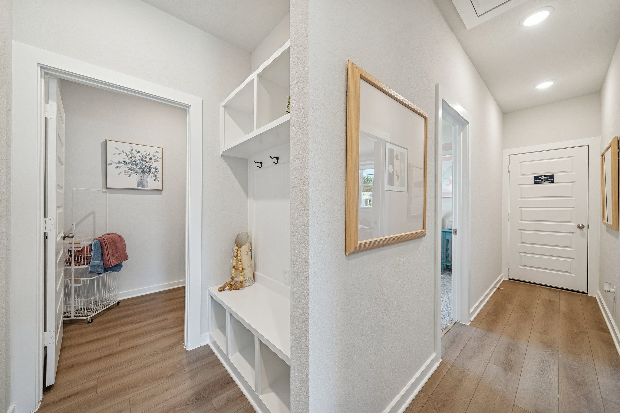 Mudroom entryway at Spring Branch Crossing in Conroe Texas with built-in bench, coat hooks, laundry basket, and hardwood floors
