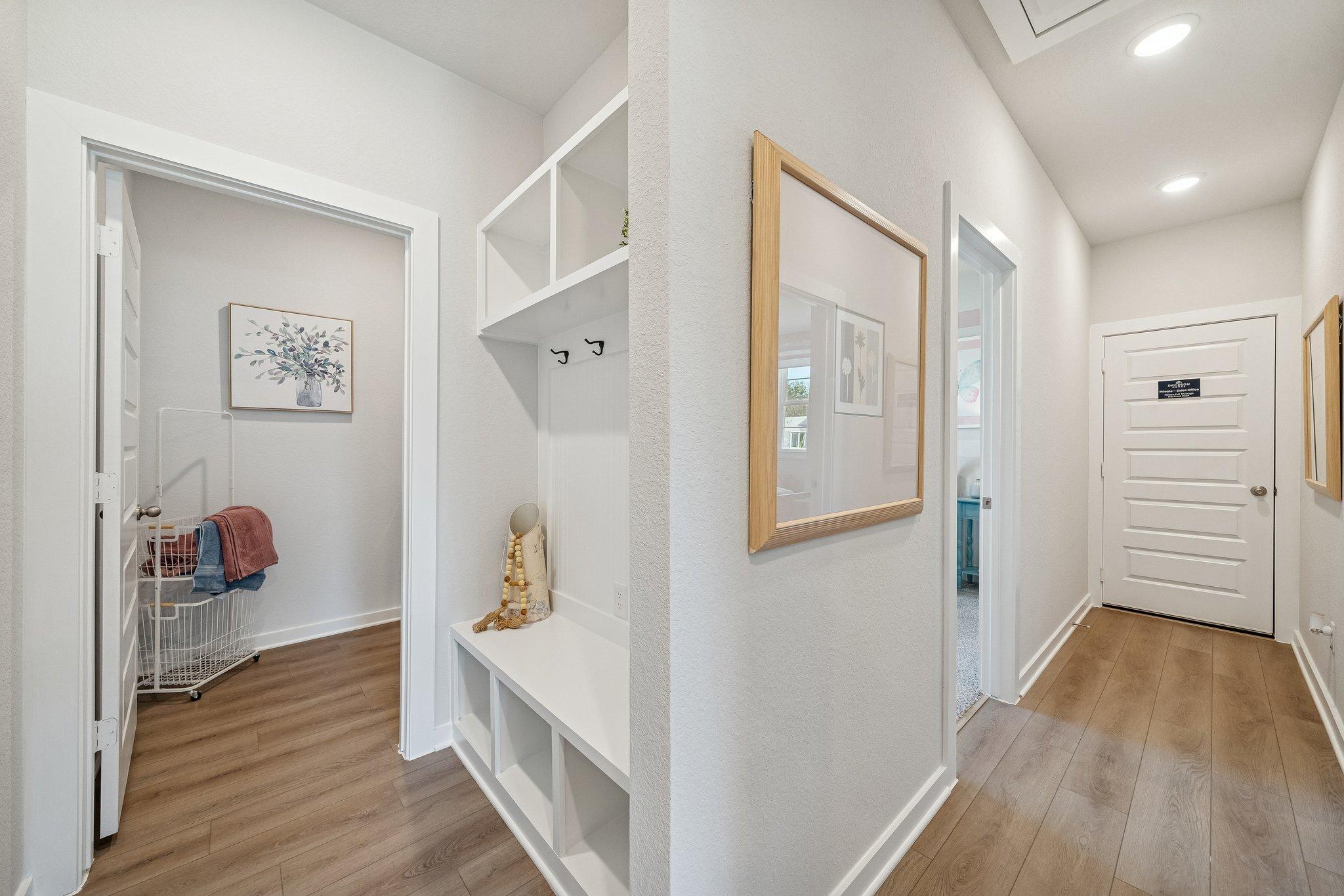 Mudroom entryway at Spring Branch Crossing in Conroe Texas with built-in bench, coat hooks, laundry basket, and hardwood floors