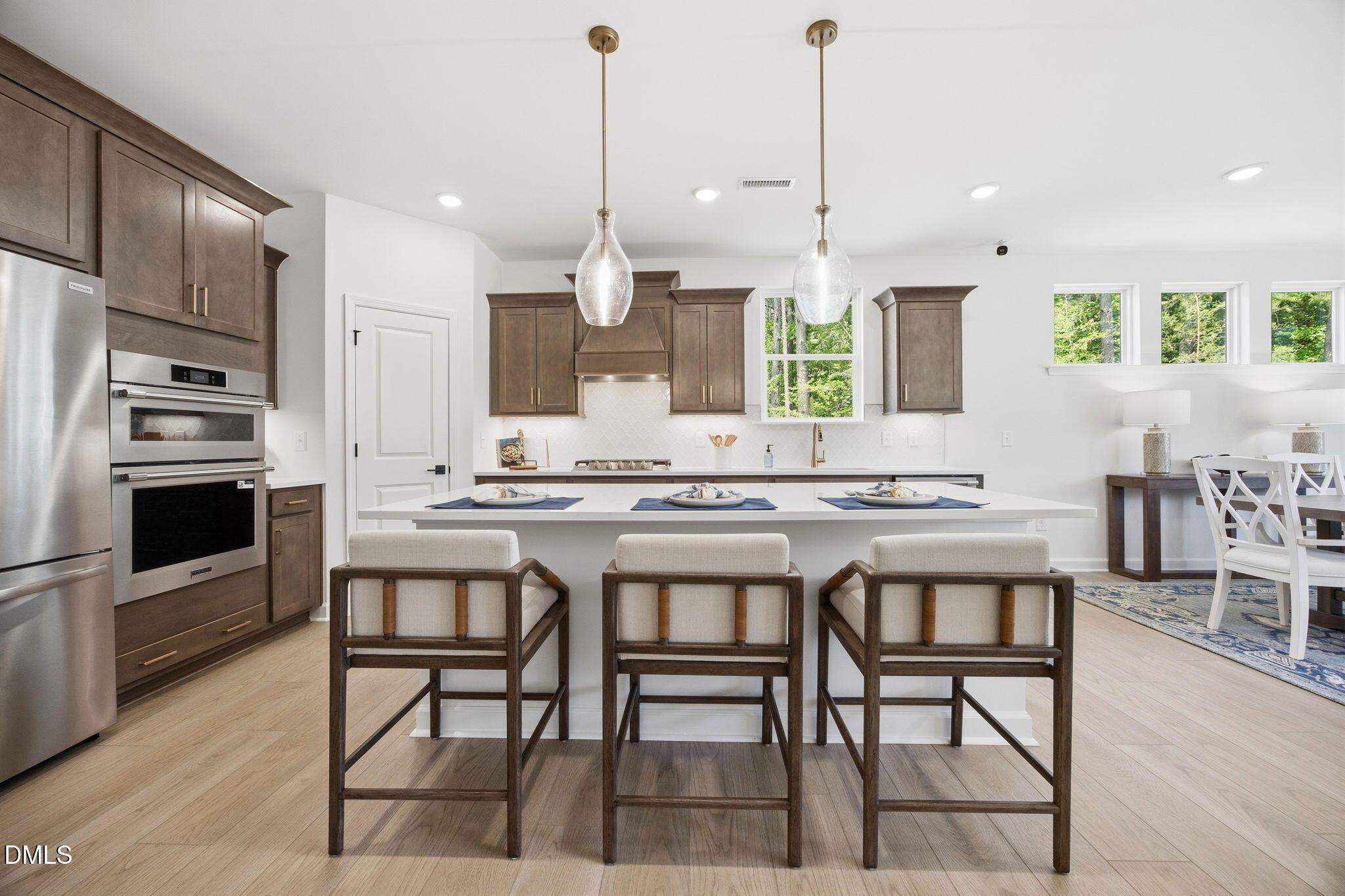 Modern kitchen with large island and stainless appliances in The Ashport M floor plan at Wendell Ridge, North Carolina.