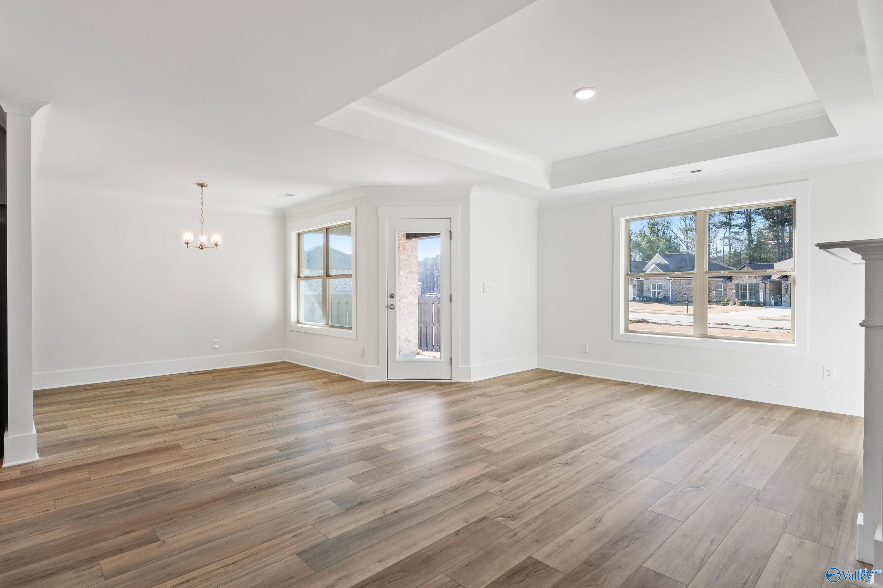 Elegant formal dining room with tray ceiling, chandelier, hardwood floors, and French doors in The Daphne C by Davidson Homes, Arab, AL